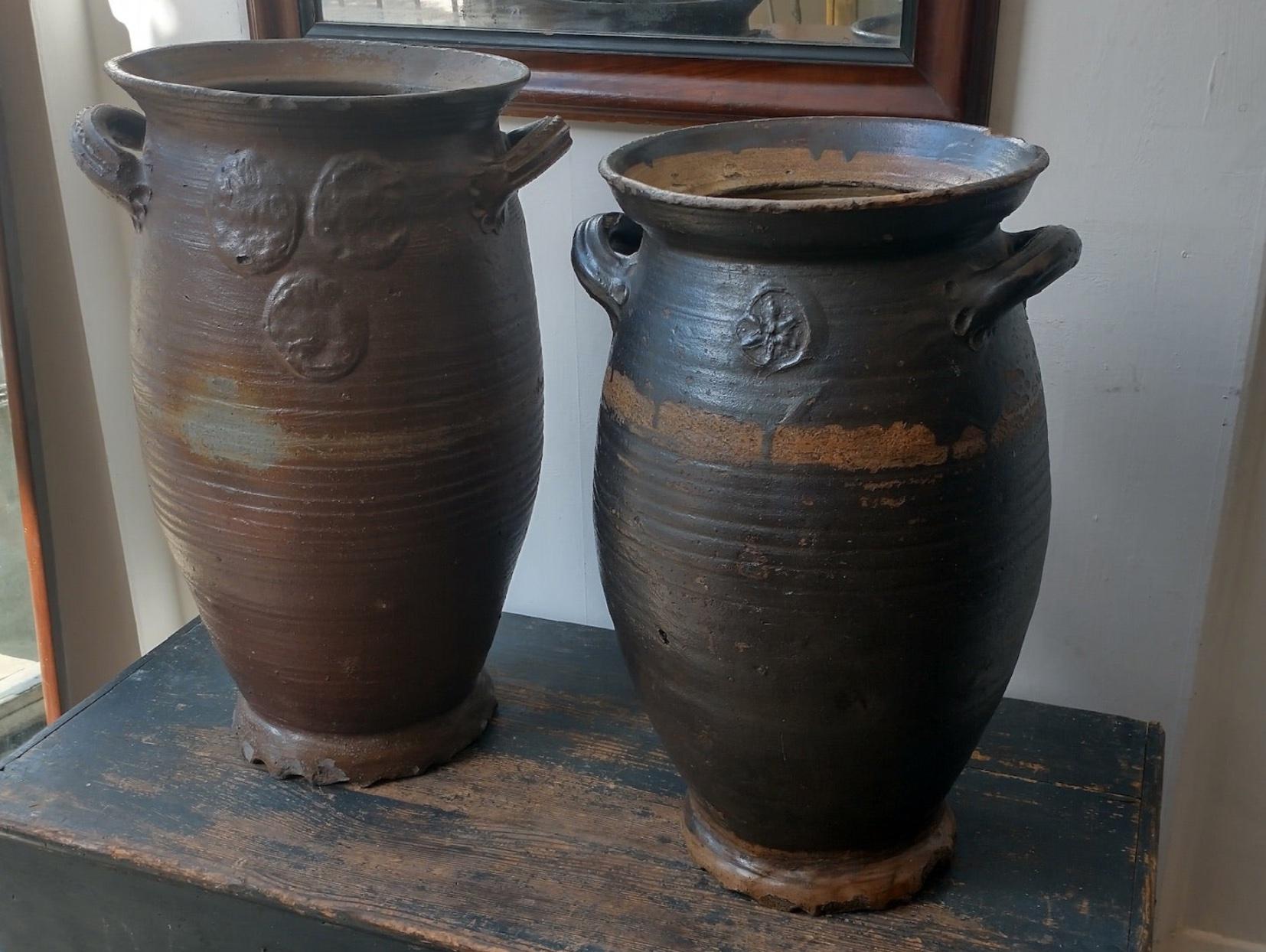 Pair of large 19th century stoneware pots with dark brown semi-matte glaze, two petit carrying handles, and maker's embossed insignia. 

Germany, circa 1870

Dimensions: 22W x 16D x 15H