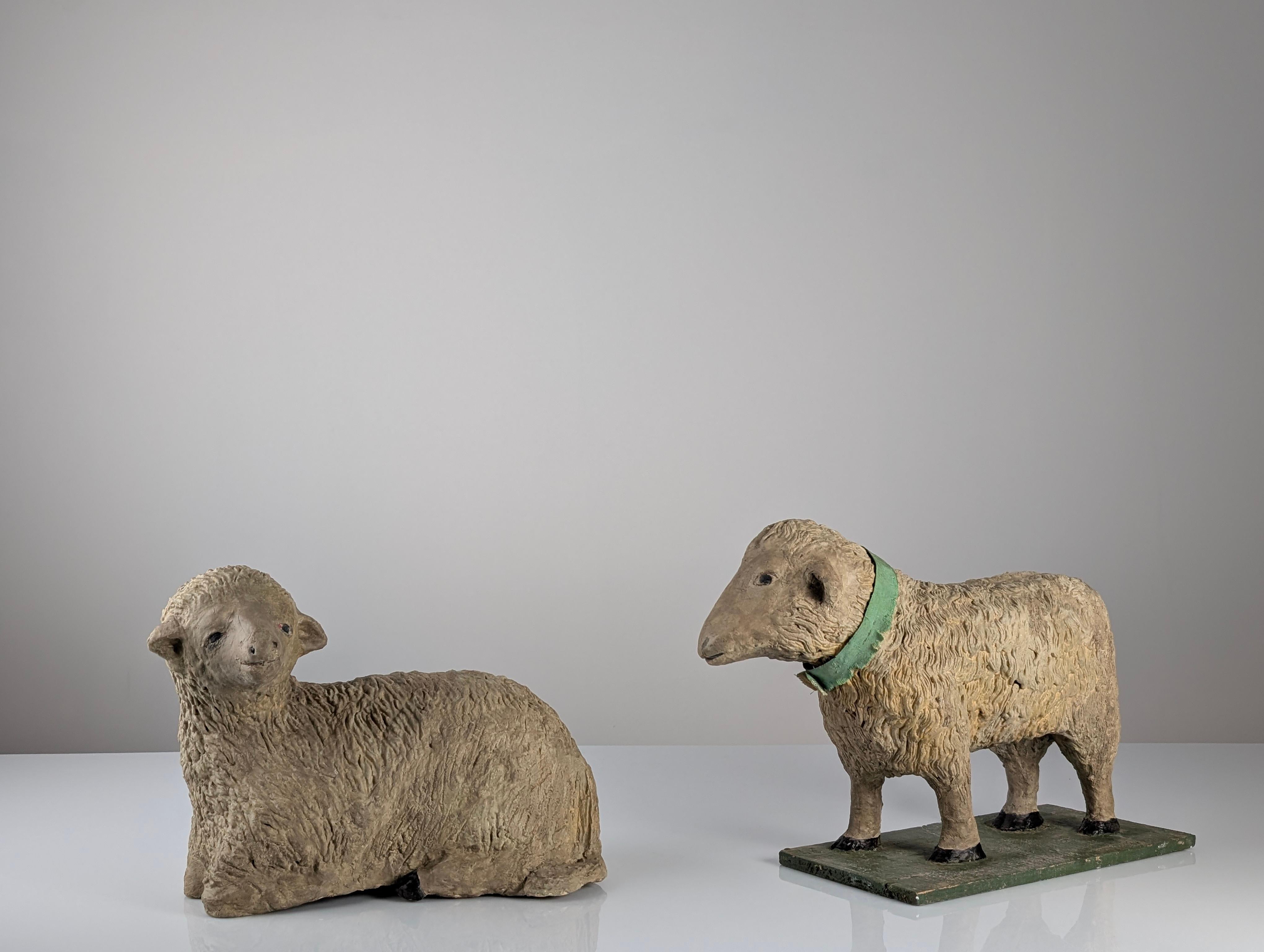 This charming pair of large, handcrafted stucco or plaster sheep sculptures dates from the early 20th century, representing European folk art. The set includes one reclining lamb and one standing sheep. The modeling is rustic and naturalistic,