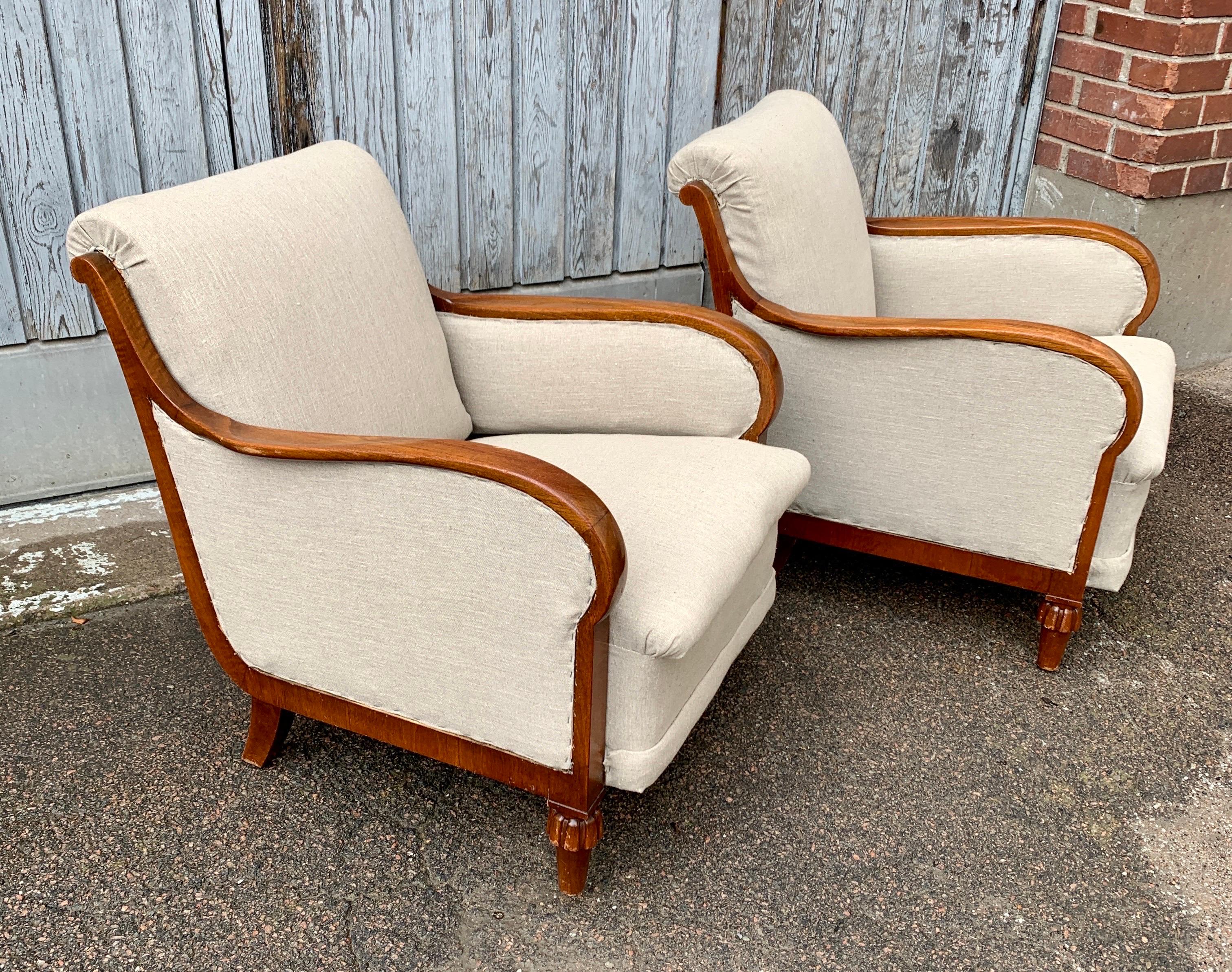 Pair of stylish, as well as comfortable, Swedish Grace club or lounge chairs in beige fabric with formed wooden armrests from the first part of the 20th Century. This important period of Swedish furniture design research not only has the look and