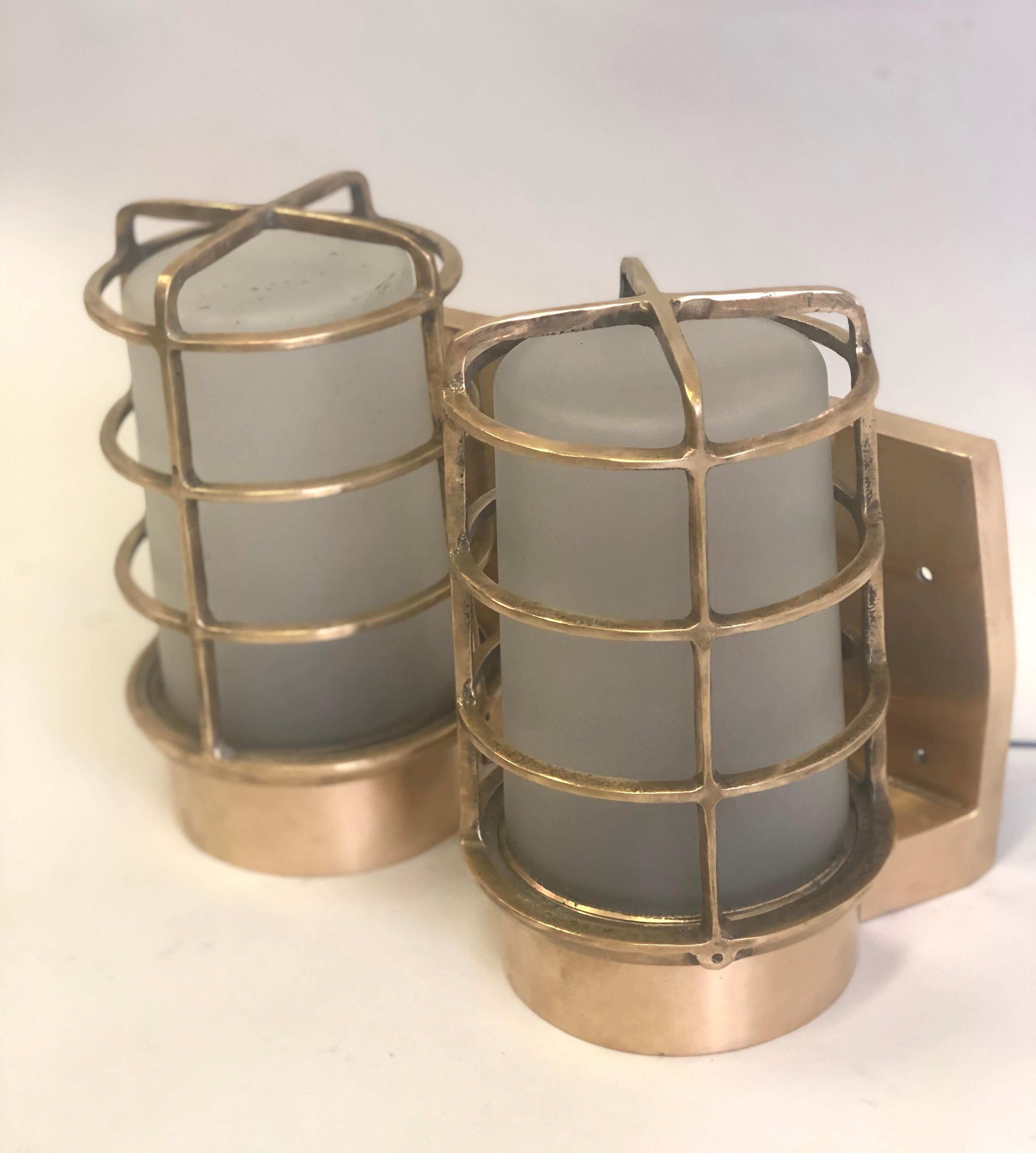 An elegant and exceptional pair of large Swedish Marine industrial wall lights or sconces in heavy, solid brass with satinized glass reflectors / shades, circa 1930.

These pieces from a decommissioned Swedish ship reflect the highest quality of