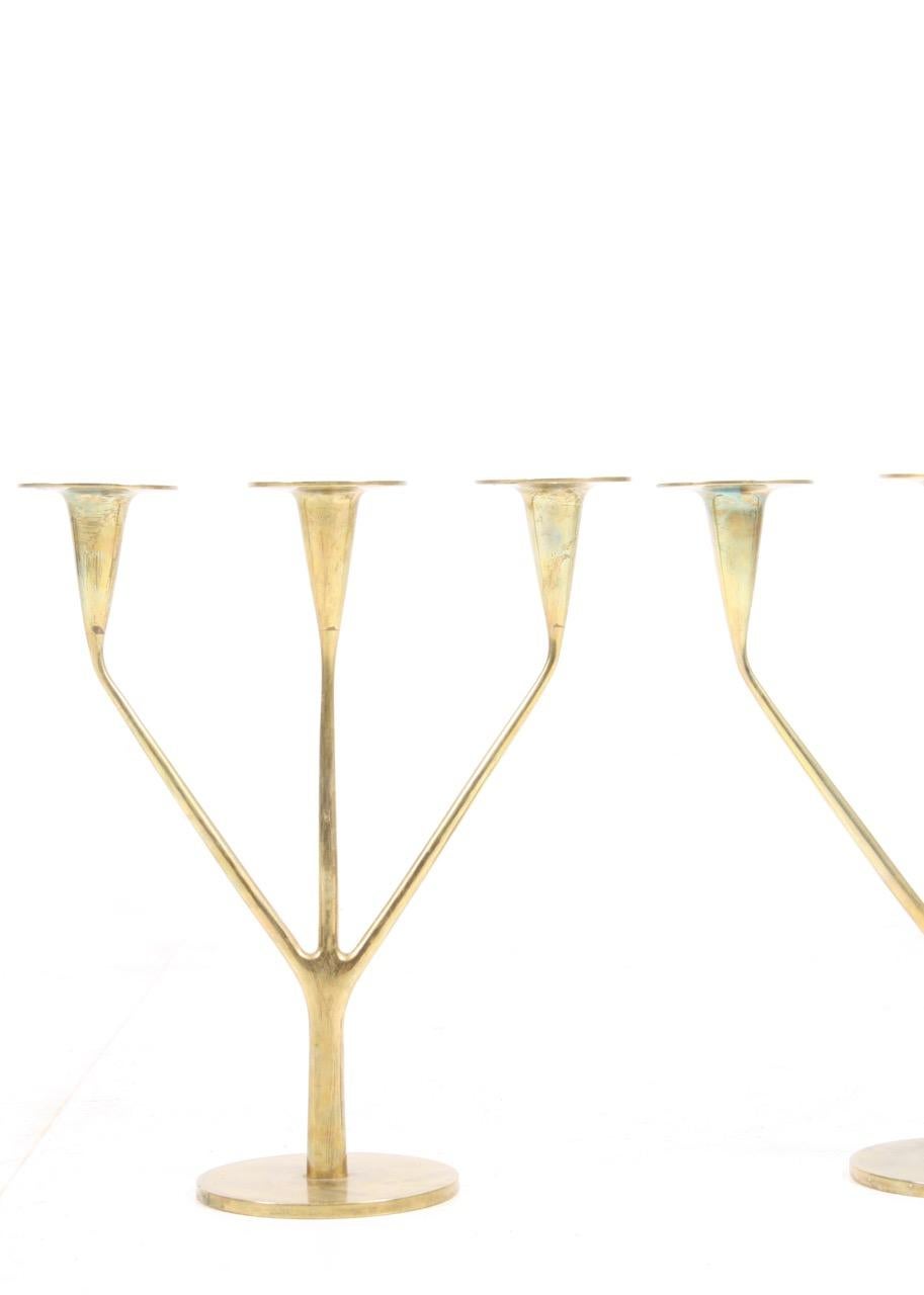 Pair of candelabras in solid brass, each pair holds three candles. Made in Denmark for Illums Bolighus in the 1950s.