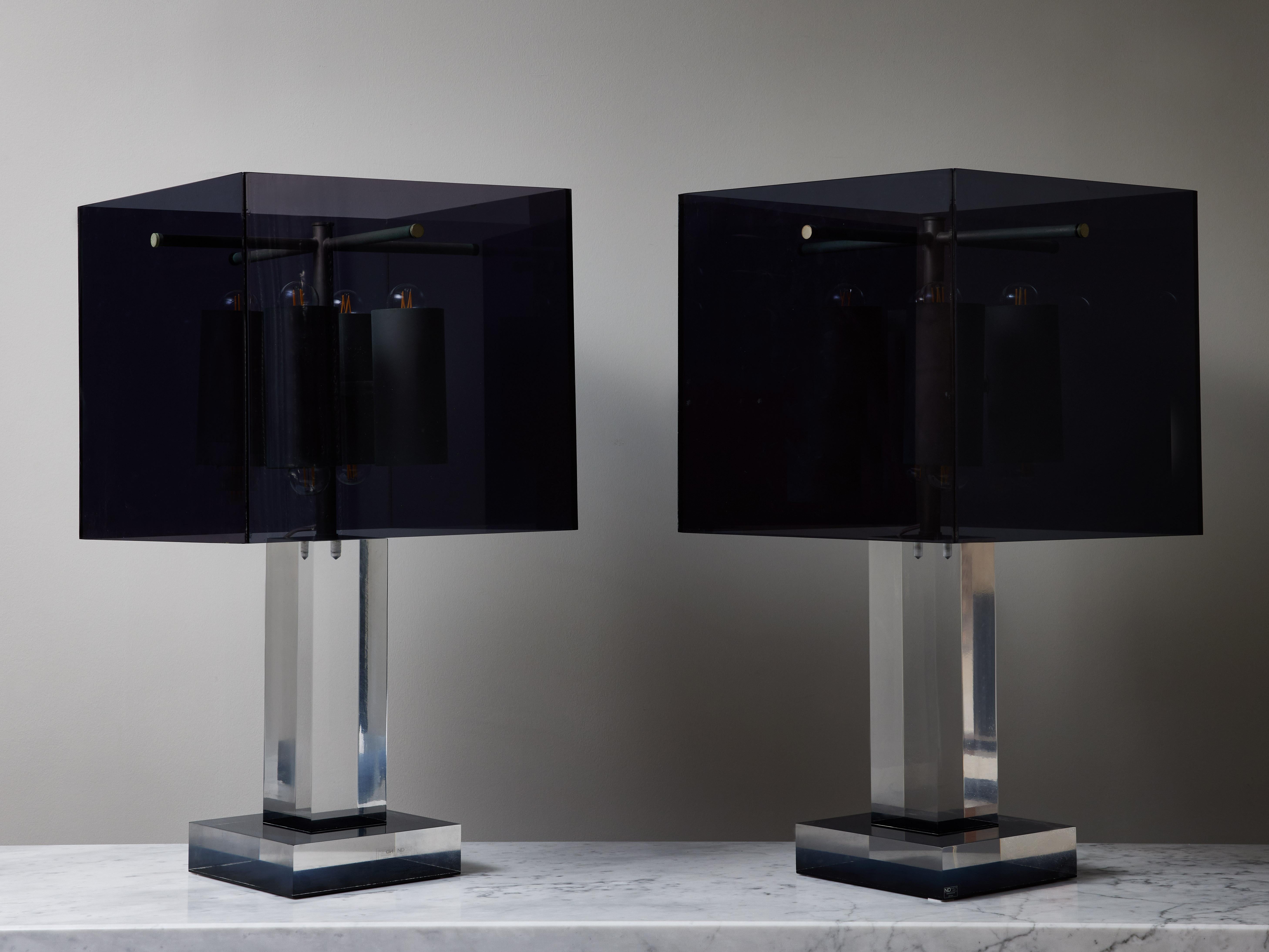 Pair of imposing square table lamps made of clear lucite body and dark grey lucite lampshade. These have height lights per lamp allowing them to provide quite a lot of light despite the dark shade.

Original sticker of the manufacturer on the