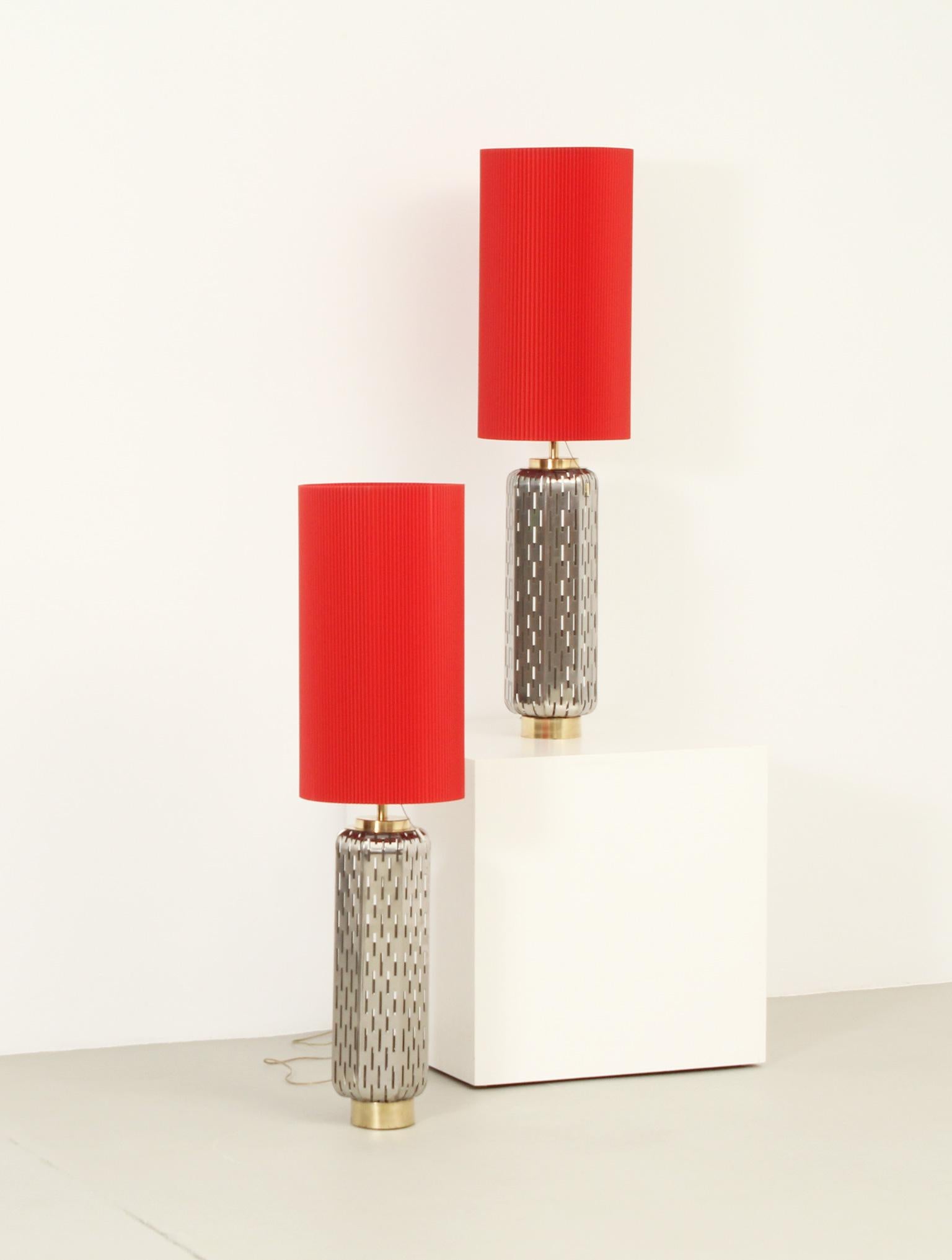 Pair of large table lamps from 1960's, Spain. Unusual design with bases in perforated steel plates supported by brass pieces. Double shade in corrugated red plastic that slides over another interior one in translucent plastic. 