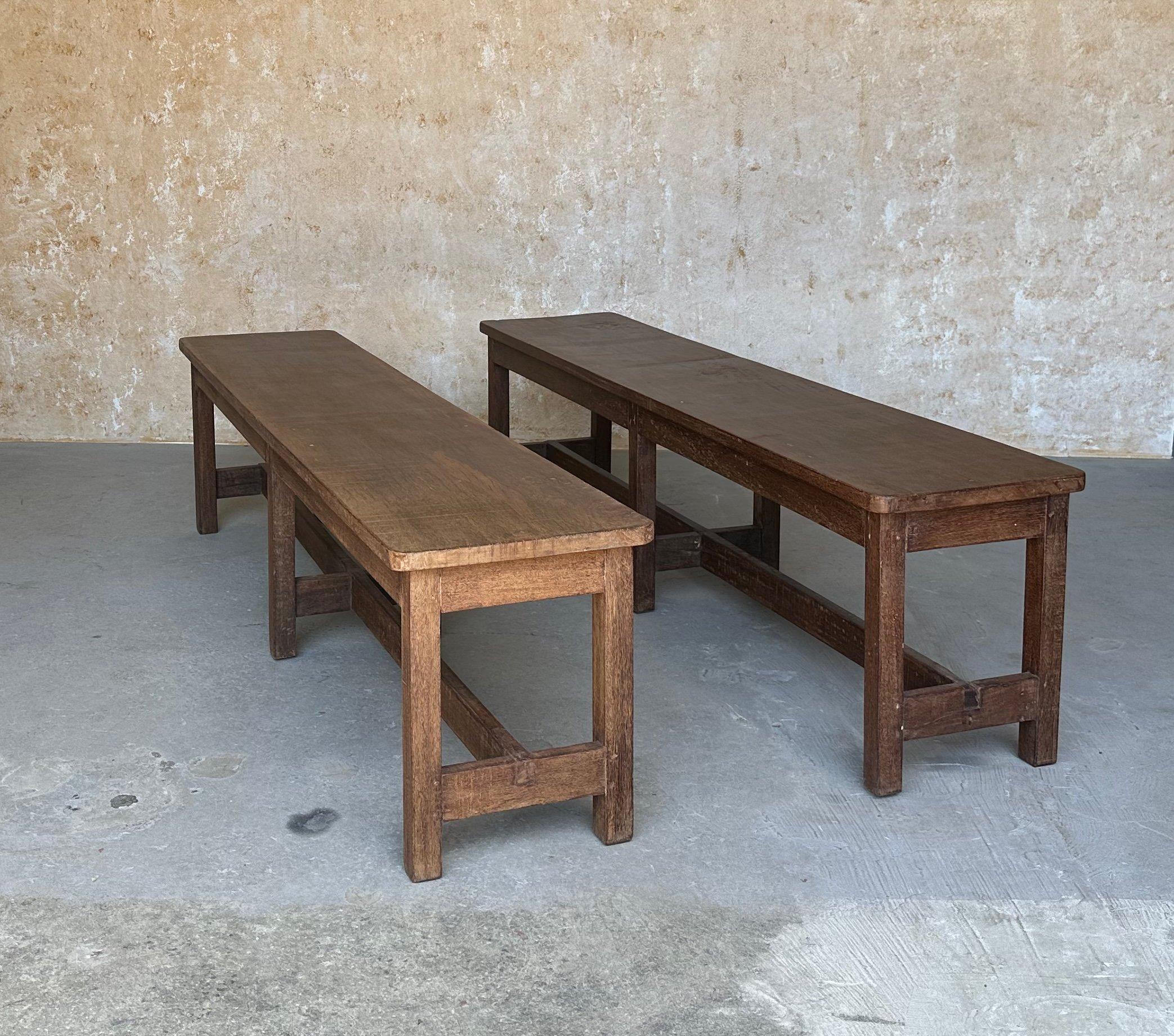 An unusual pair of large benches made of solid teak wood that feature stretchers supported by a central set of legs. The benches were most likely made in India at the beginning of the 20th century and have a wonderful patina that shows signs of wear