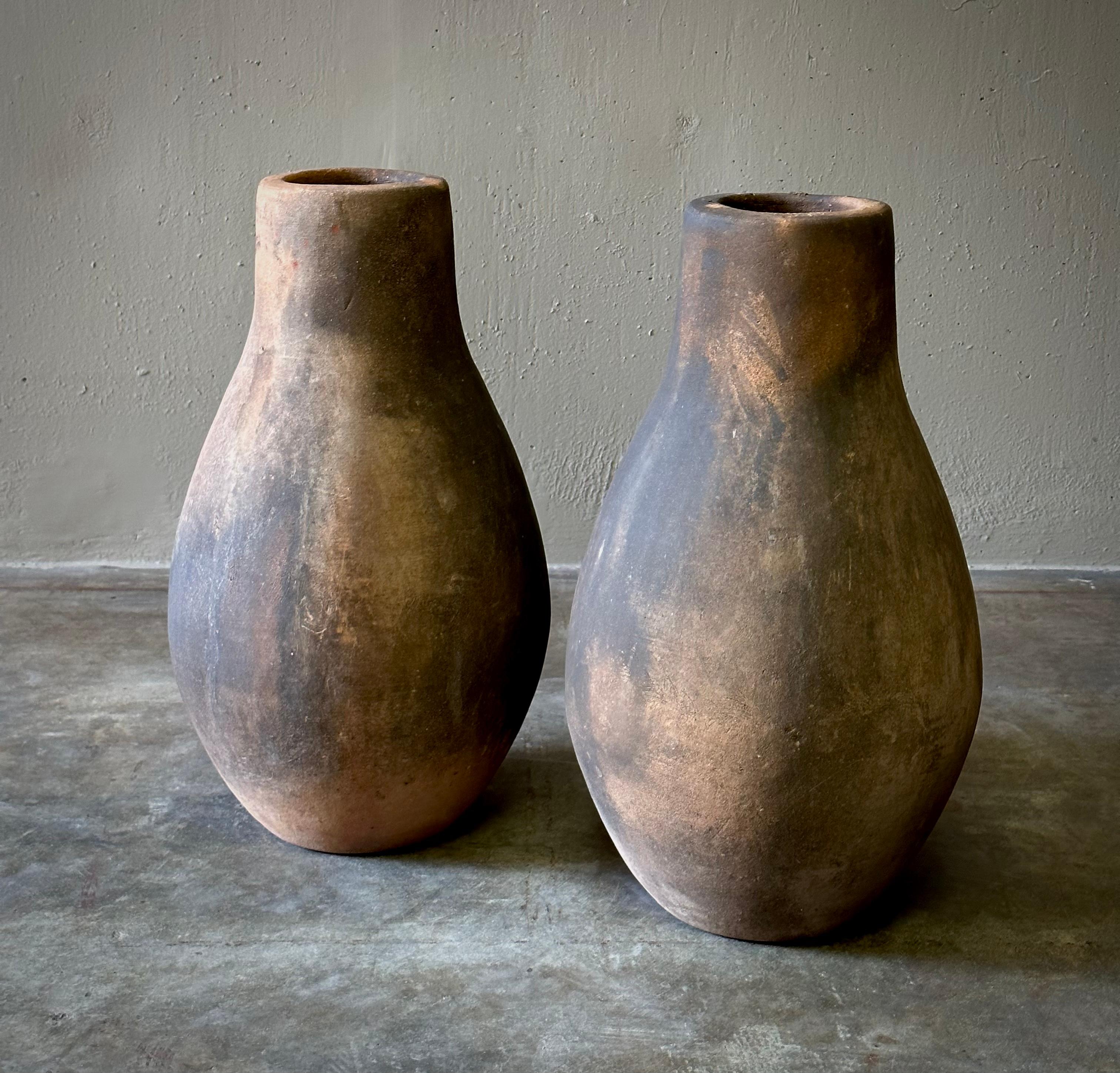 Pair of decorative terracotta vessels from Jalisco, Mexico with simple, elongated shape and smoky, rustic patina. Wonderful displayed as a pair or separately. 

