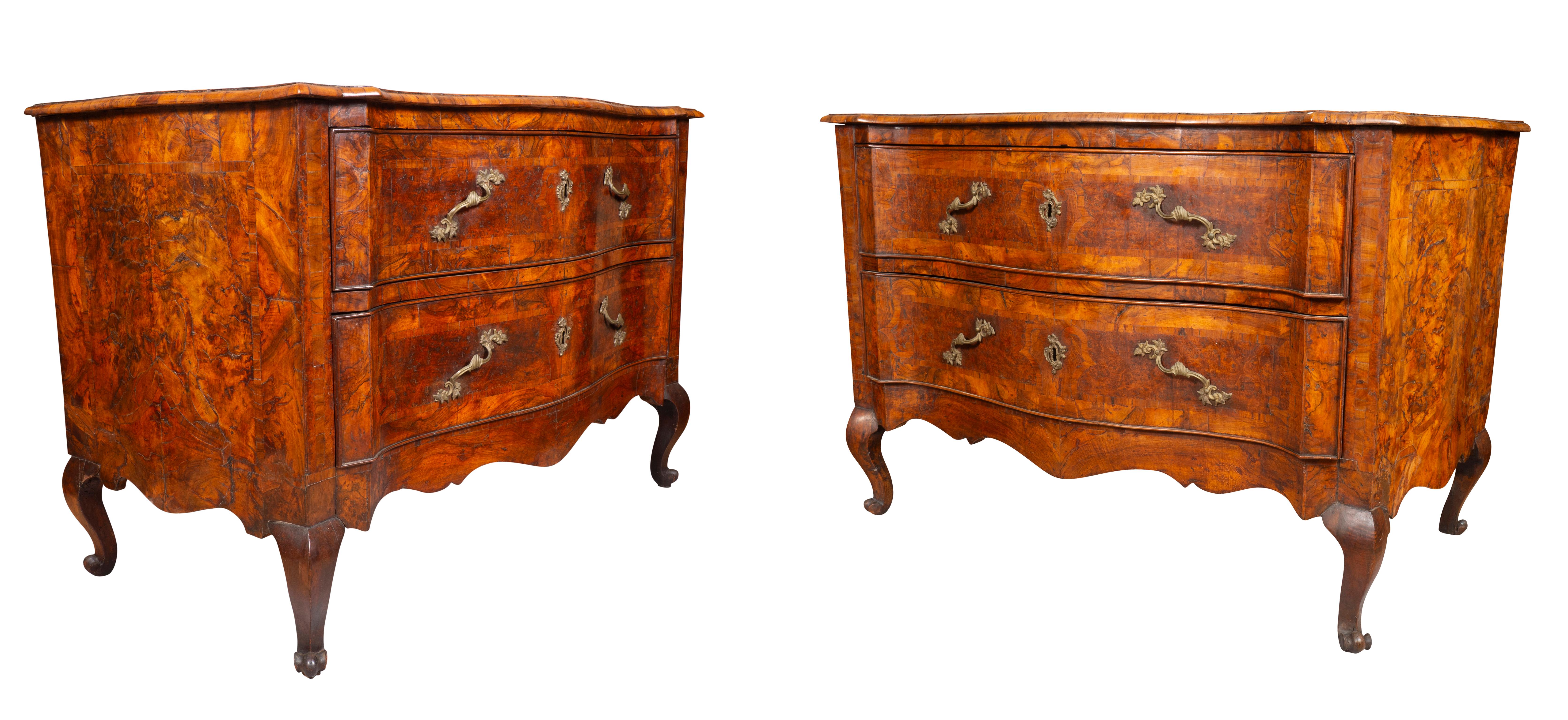 A fine pair of commodes in remarkably good condition. With serpentine rectangular top with book matched veneer over two conforming drawers with cast brass rocaille handles, raised on cabriole legs and scroll feet.