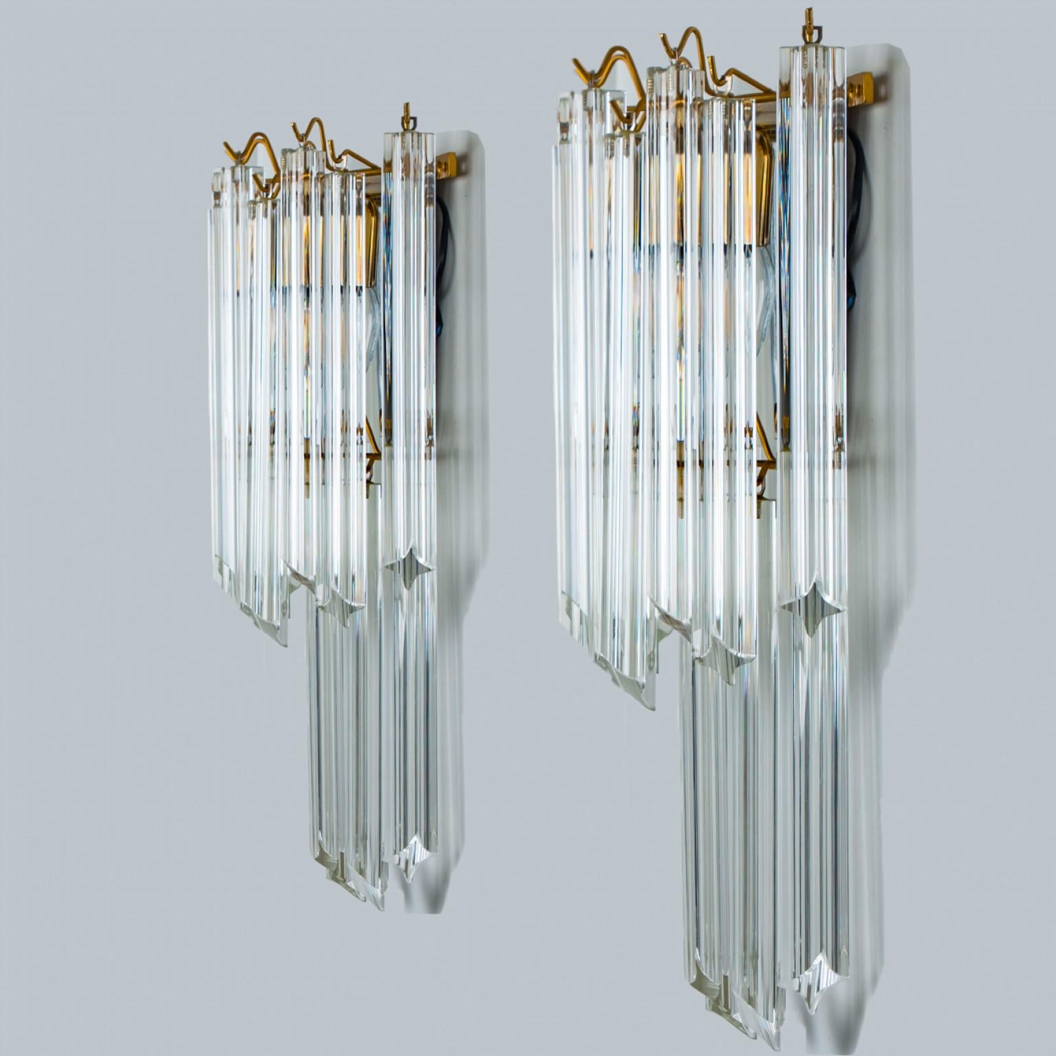 Pair of eautiful triangle shaped glass wall sconces featuring multiple long crystal clear glass tube-like rods, with brass details and back plate. Illuminates beautifully. High-end pieces.

Cleaned and well-wired, in full working order and ready to