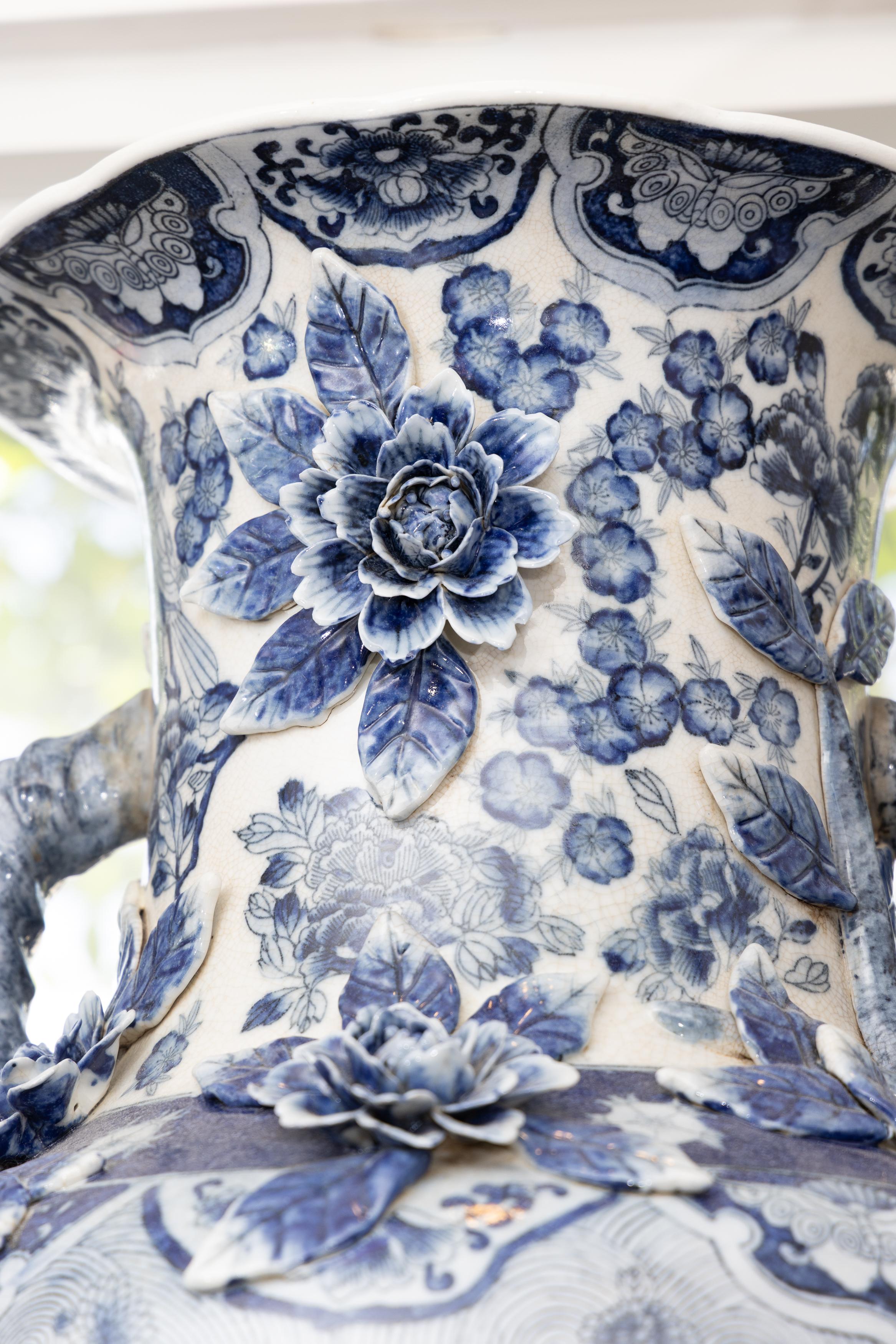 Un'importante coppia d'epoca di vasi in porcellana orientale, ciascuno a forma di urna e decorato con disegni floreali e architettonici in tonalità di blu su fondo bianco.  Il collo con manici contrapposti forma un movimento a corda attorcigliata. 