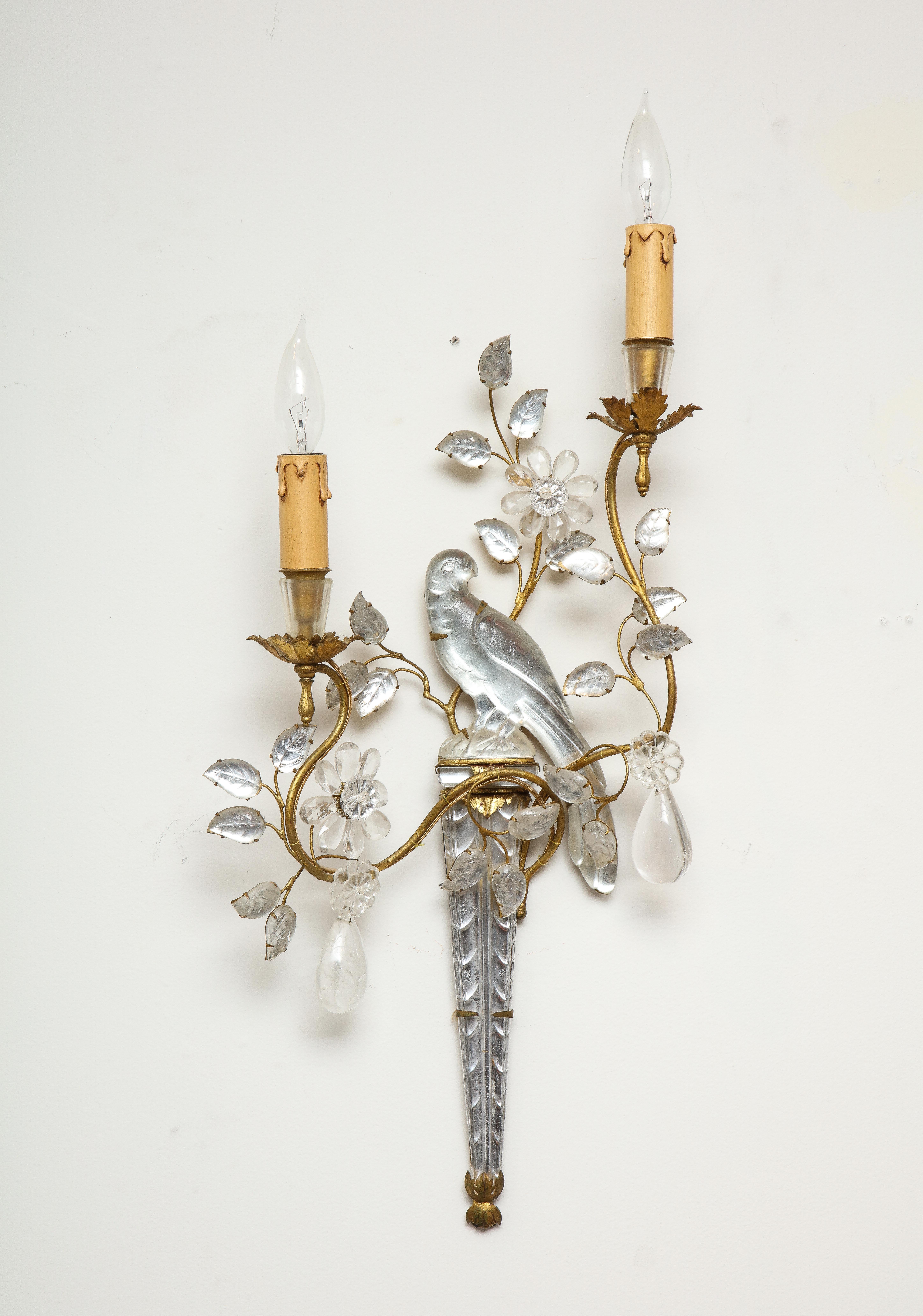 An impressive pair of large vintage Maison Baguès rock crystal sconces.    Carved birds sit atop decorated long vases held in an obtrusive brass frames. Rock crystal pendants dangle from the tendril and rock crystal leaves surround a floral base for