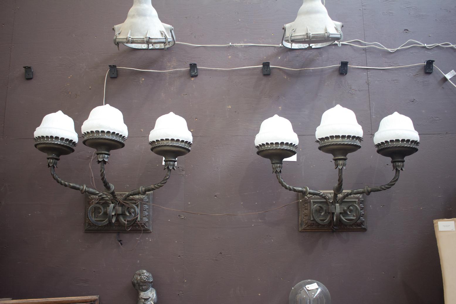 This is an amazing pair of substantial wrought iron vintage triple arm exterior wall lights from a commercial building in Portugal. They have new wiring and glass shades.
 