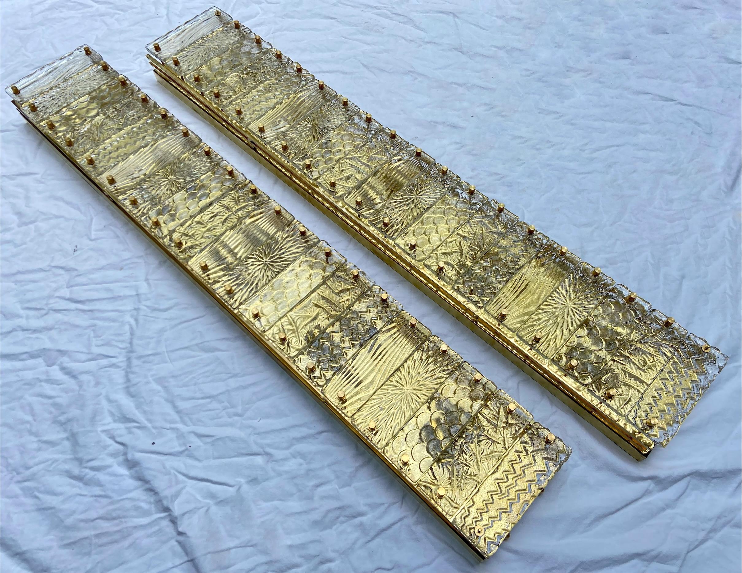 Pair of large wall lights - Italy - Circa 1980
Structure in brass and riveted Murano glass plates.
The brass plate gives this golden effect to the glass plates
Measures: L 115 x W 18 x D 9 cm
In perfect condition.