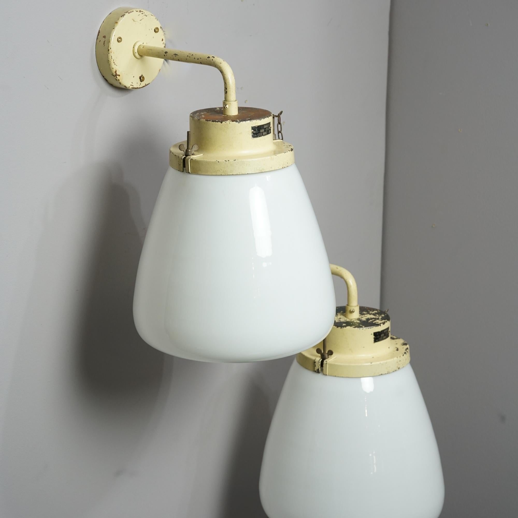 Pair of large wall lights by Paavo Tynell for Taito Oy from the 1940s. Painted metal frame with milk glass domes. Manufacturers stamp. Good vintage condition, patina and wear consistent with age and use on the metal parts. The lights are sold as a