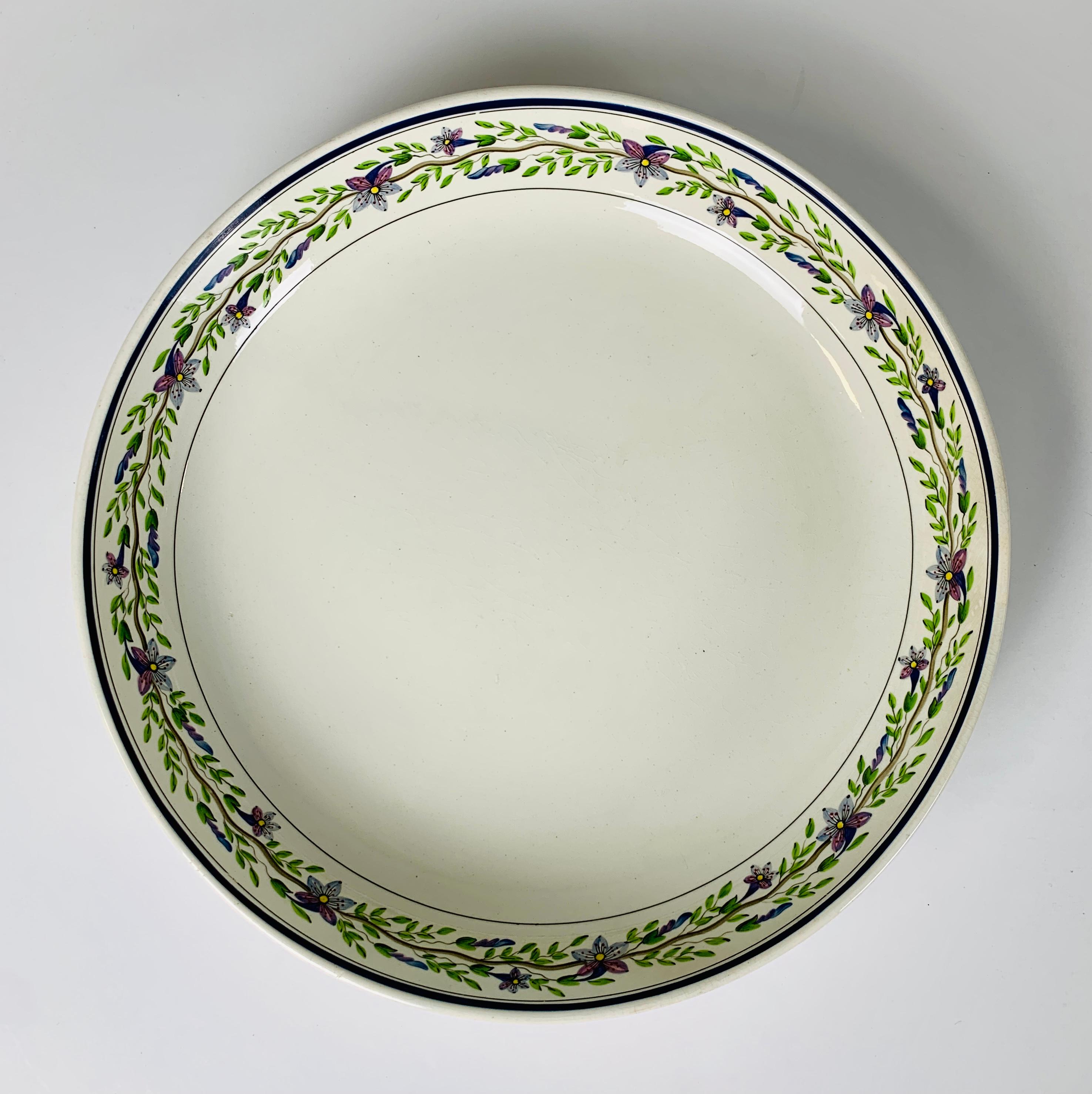 A pair of large Wedgwood bowls their borders painted with a lovely, delicate vine with lavender and lavender-pink flowers and green leaves. 
They are understated and beautiful!
The underside of each bowl is marked with an impressed 