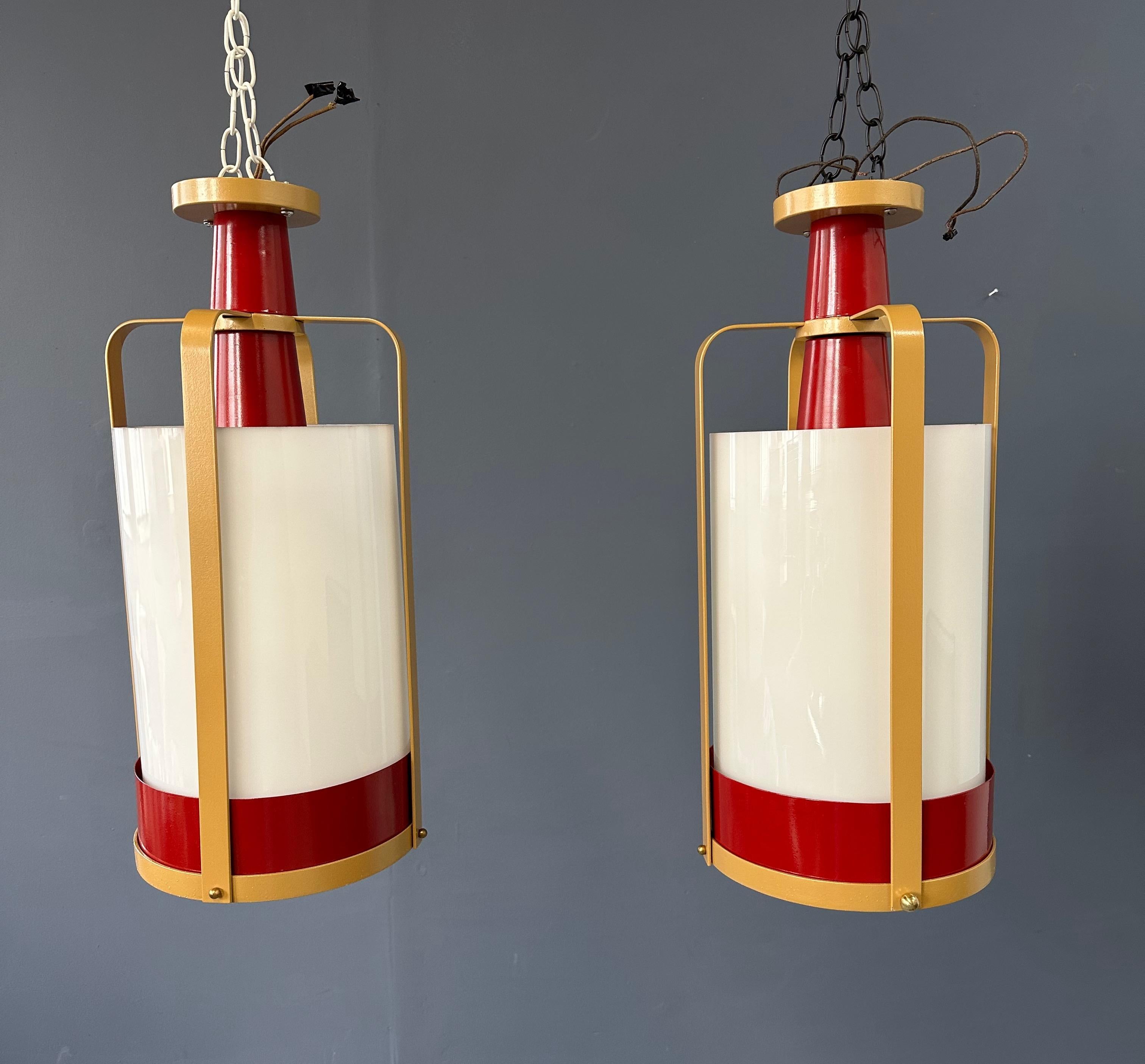 Queste grandi luci a sospensione in vetro bianco sono caratterizzate da una splendida cornice in ottone e rosso, che aggiunge un tocco di eleganza e raffinatezza a qualsiasi spazio. Grazie alle loro dimensioni generose, forniscono un'ampia
