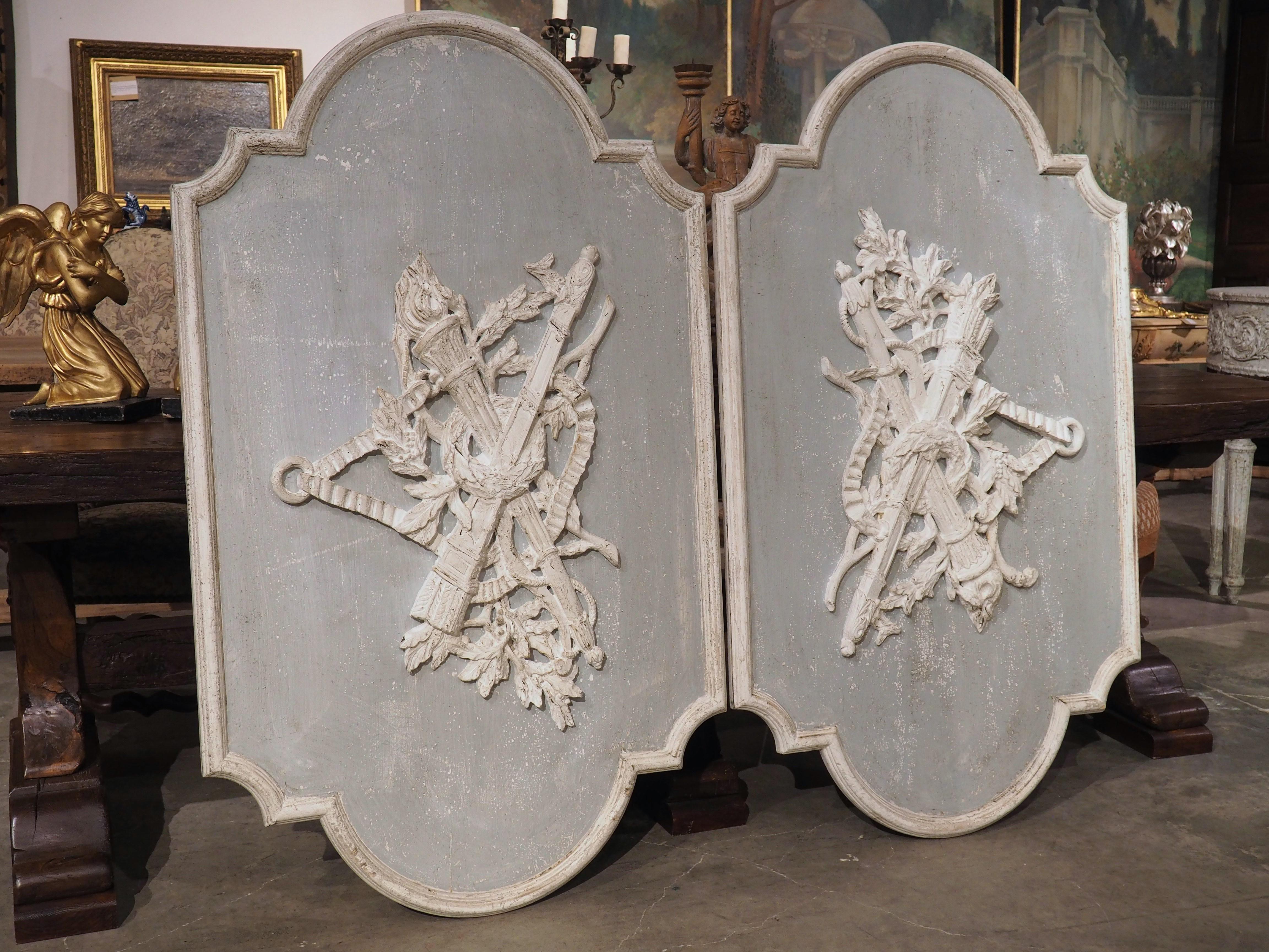 Carvings with a military, musical, hunting, or agricultural theme, known as trophies, became popular during the period of Louis XVI. This pair of large trophy panels have Neoclassical motifs (another hallmark of Louis XVI) painted in white over a