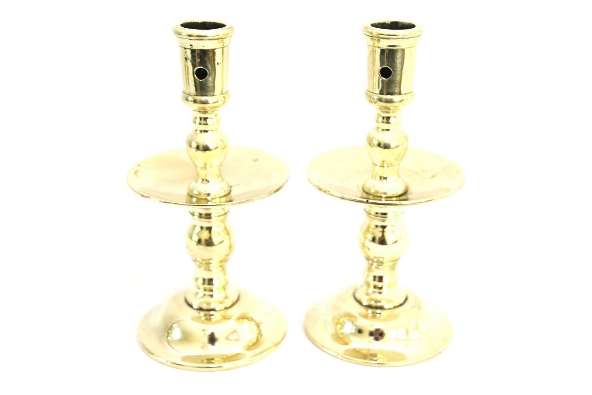 Pair of late 17th-early 18th century European (likely Dutch or Portuguese) brass candlesticks of seamed construction with extracting hole to each side of candle cup and baluster knobs to stem on either side of medial dished drip-tray, raised on a