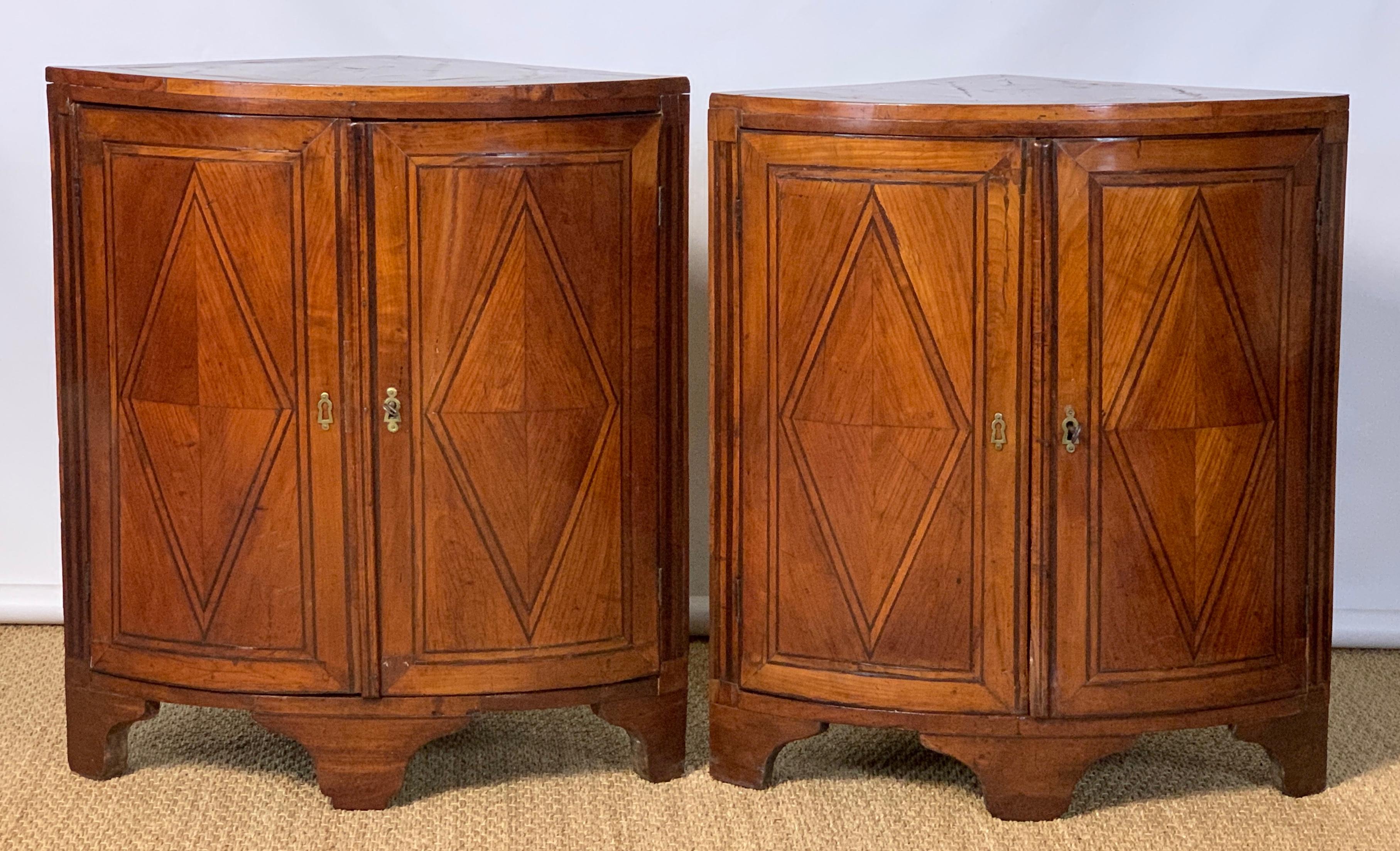 An elegant pair of late 18th century French (Louis XVI) cherrywood bowfront corner cabinets beautifully accented with ebony stringing throughout and later heathered grey marble tops.
