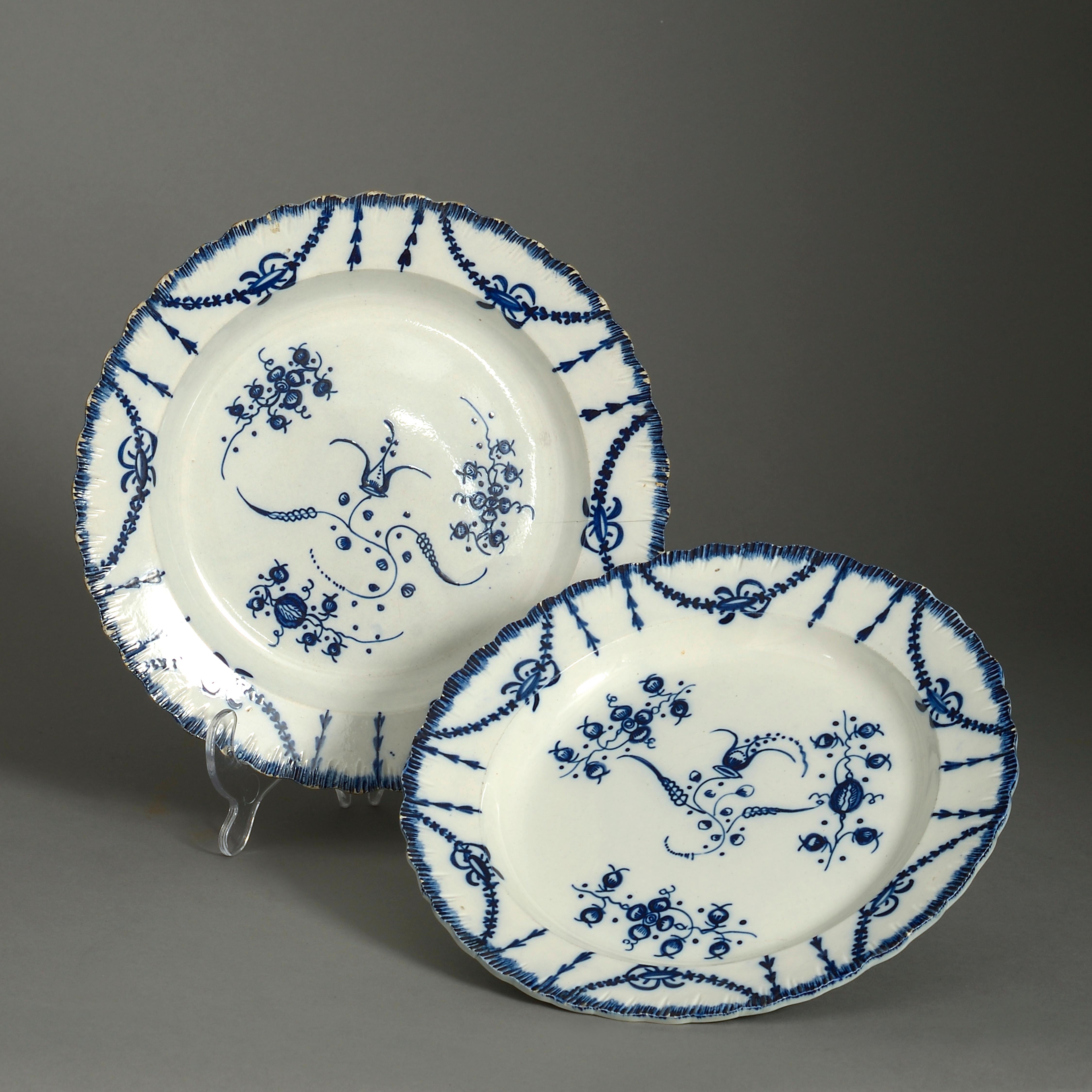 A pair of late 18th century blue and white glazed Staffordshire pottery plates, with shaped rims and decorated throughout with flowers, foliage and foliate swags. One with hairline.

   
