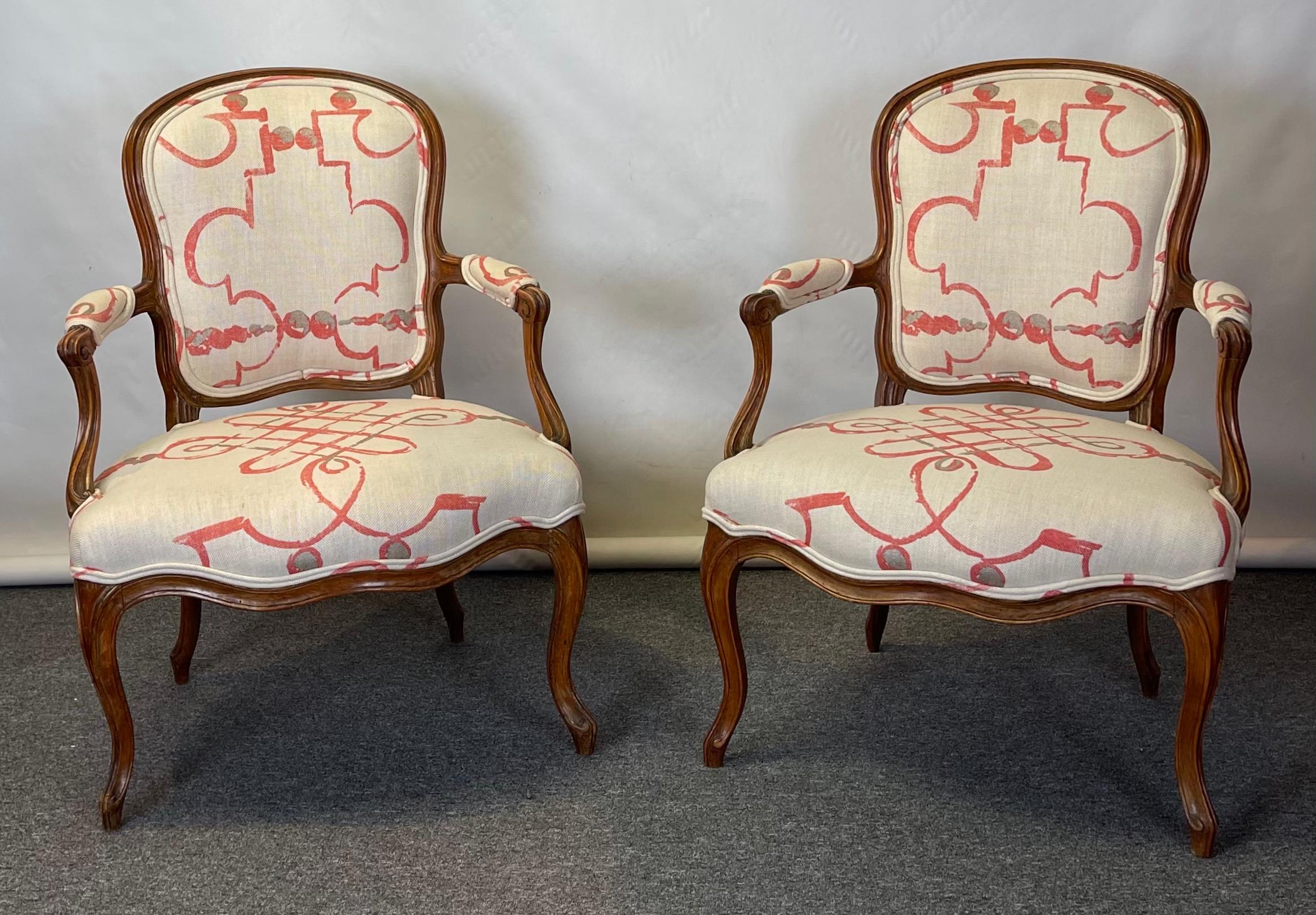 A pair of large and comfortable Louis XVI carved walnut fauteuils or open arm chairs covered in Osbourne & Little's Portavo linen fabric by Nina Campbell.