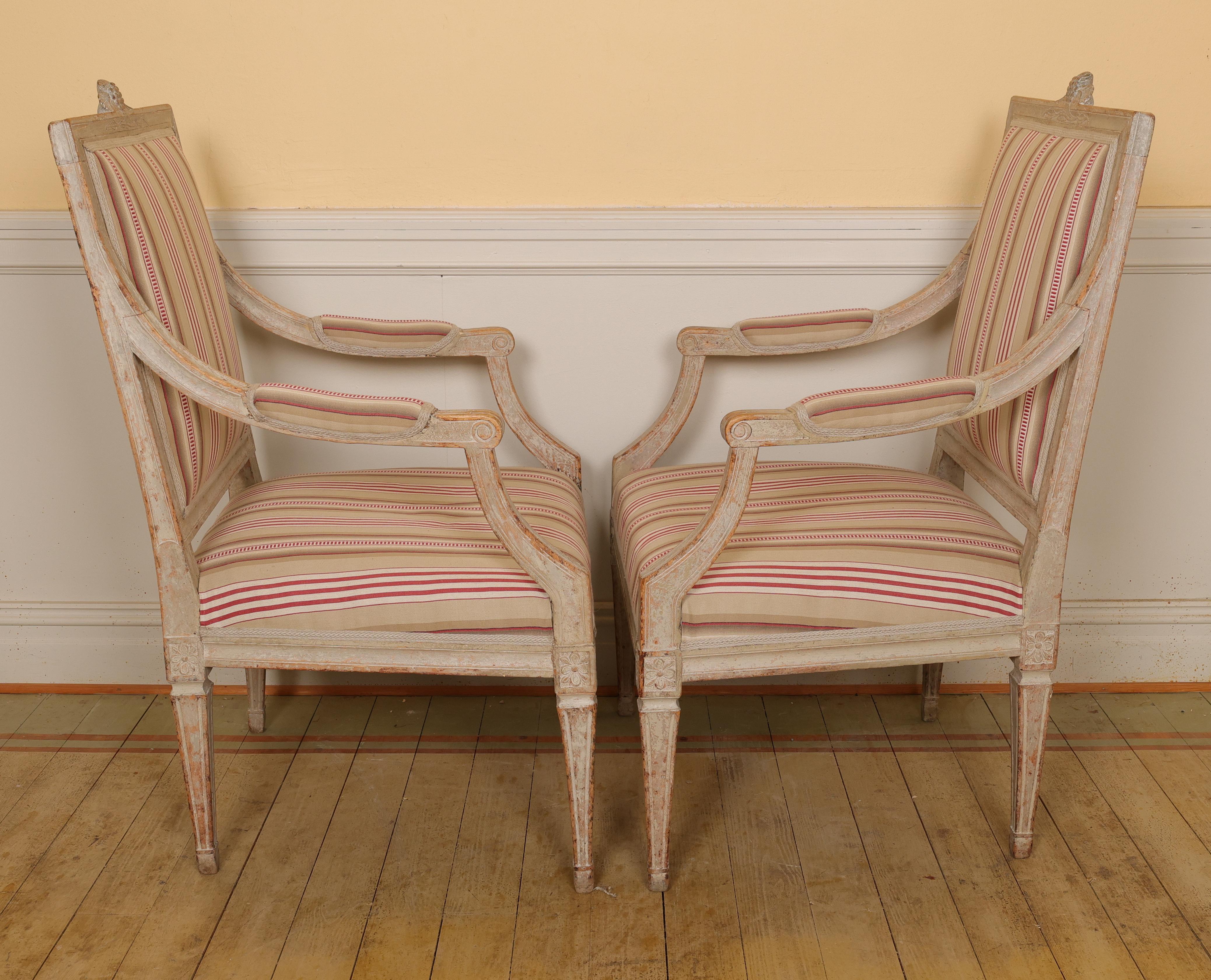 Paire de hauts fauteuils gustaviens fabriqués en Suède dans les années 1780. Ces chaises présentent un design droit avec des pieds carrés. La traverse supérieure est ornée d'un motif de vigne de houblon, dont les traces de la peinture d'origine sont