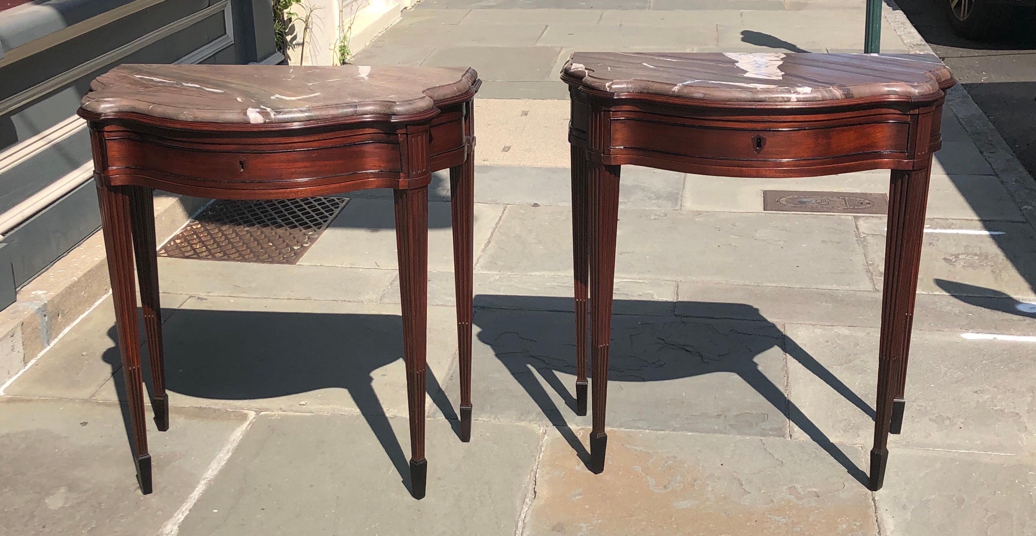 Elegant pair of mahogany neoclassical consoles with marble tops. These Classic consoles are a solid mahogany with a single-drawer. Each console has fluted mahogany legs going down to ebony stop fluting in the center of each flute. The legs are