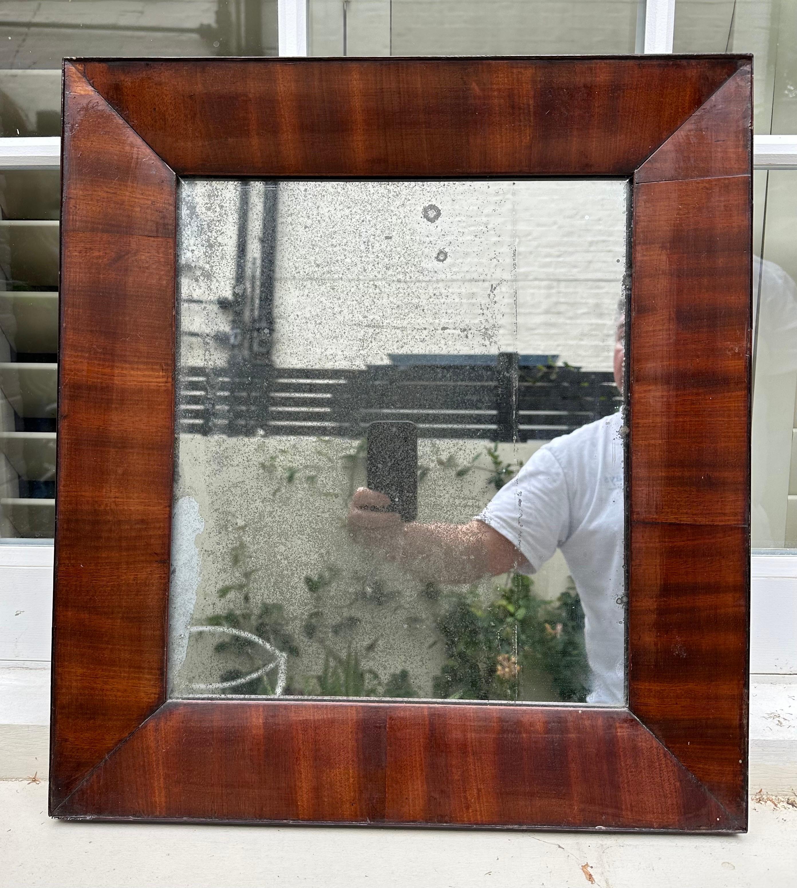 A truly decorative pair of deep red flame mahogany wood mirrors. The mirror glass has heavy patination in keeping with their age which enhances their decorative value. Extremely elegant in any interior and would complement a variety of