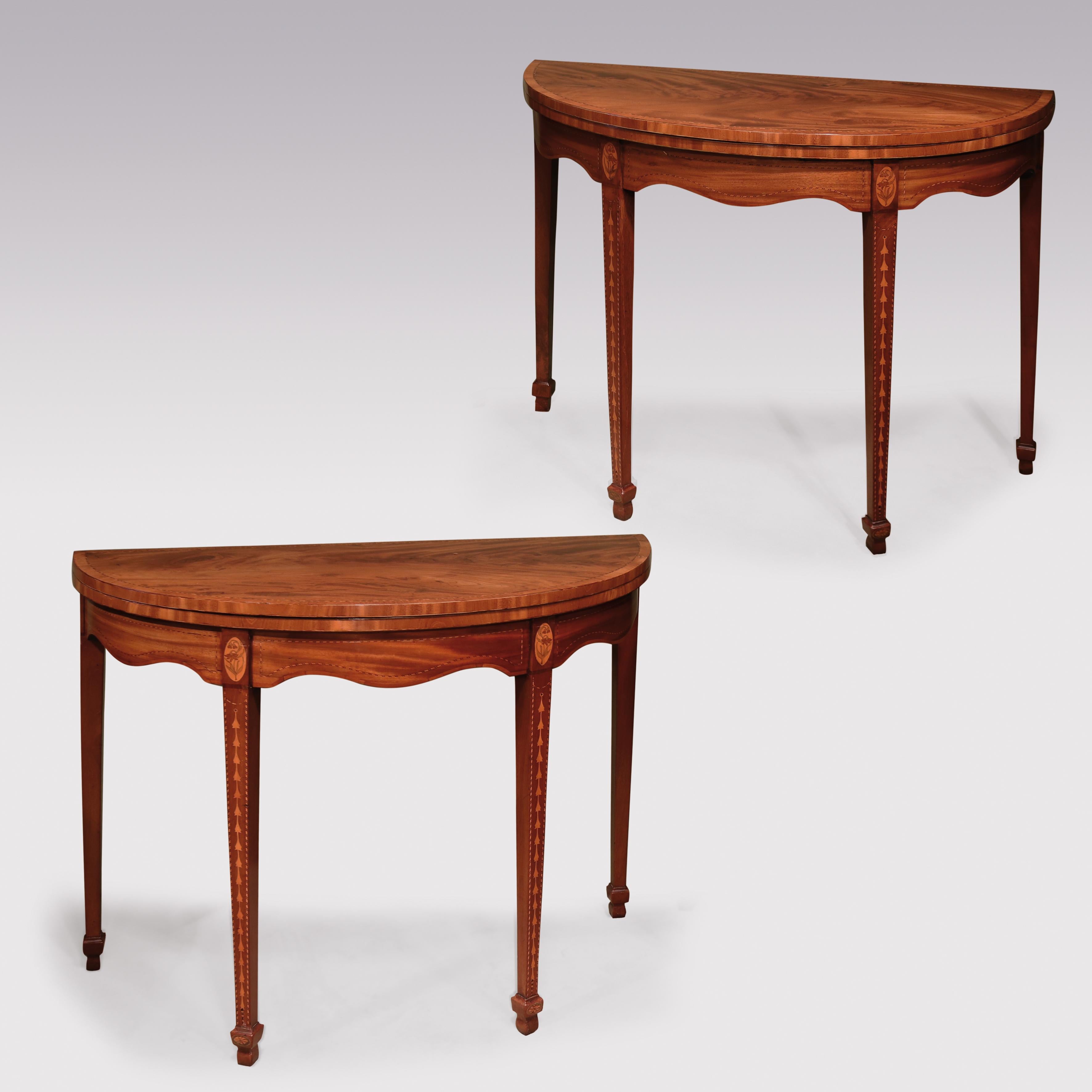 An attractive pair of late 18th century Sheraton period figured and faded mahogany card tables chequered strung throughout, having tulipwood cross-banded half round tops above serpentine shaped friezes with oval inlaid lily of the valley panels,
