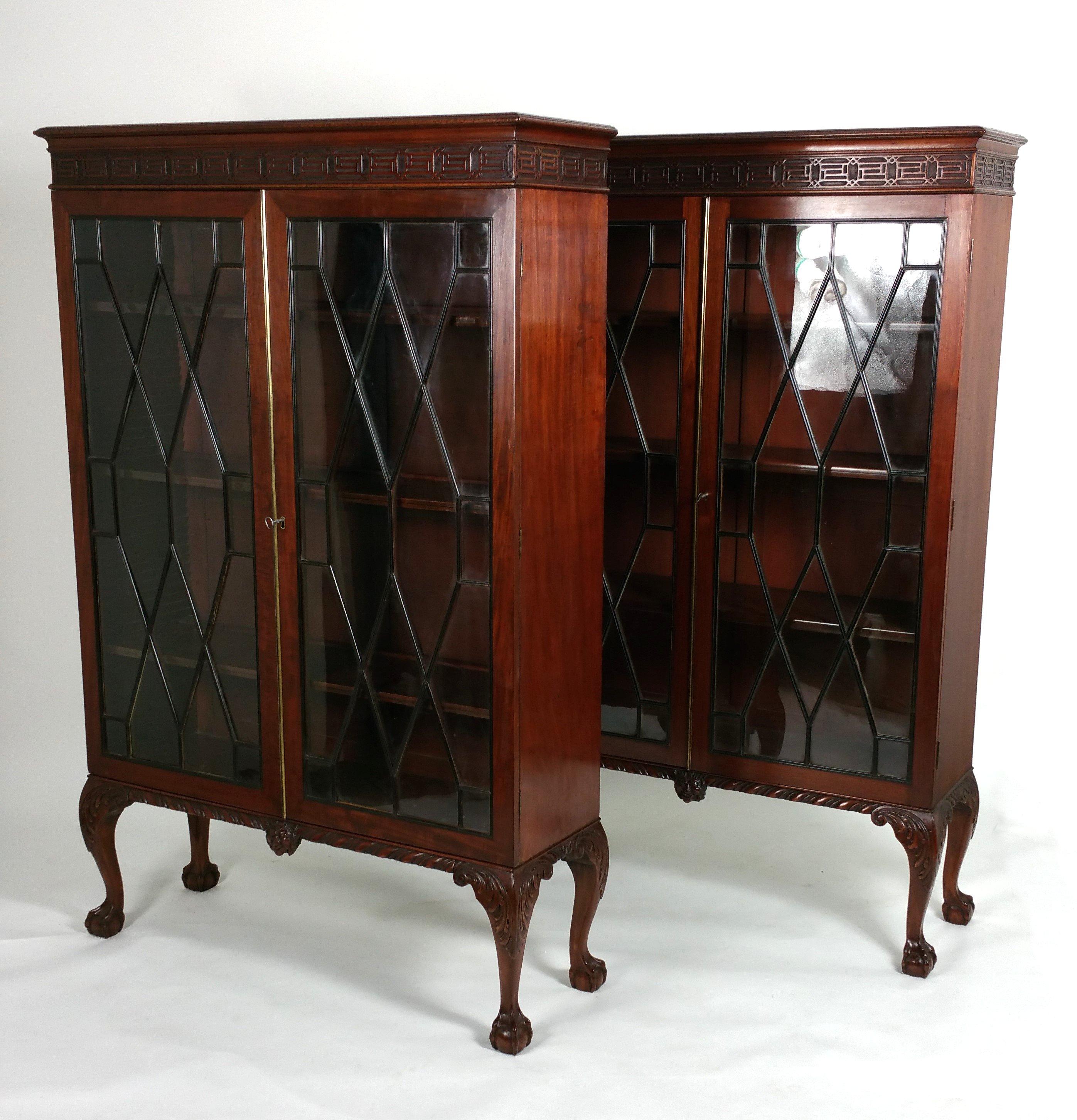 This gorgeous and very stylish pair of Chippendale revival mahogany 2-door bookcases features ebony astragal glazed doors with the original lock and key. Both bookcases have 3 adjustable ebony inlaid shelves supported on cabriole legs with a central