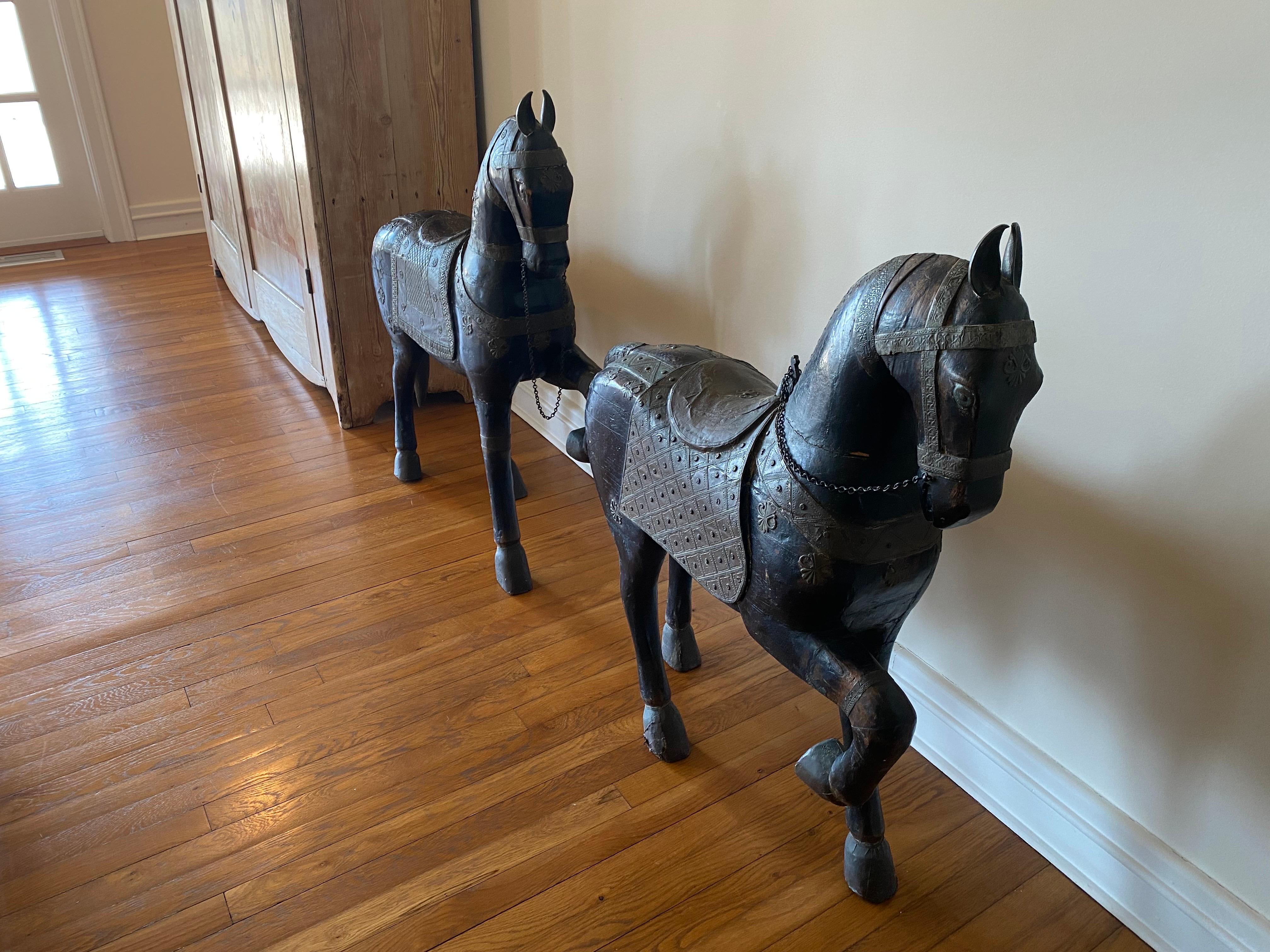 Paire de sculptures indiennes de chevaux peints en bois sculpté de la fin du 19e siècle
Chevaux en bois sculpté, peints en noir, avec des motifs métalliques élaborés sur la selle et le harnais. Usure générale, séparation et un éclat de bois sur le