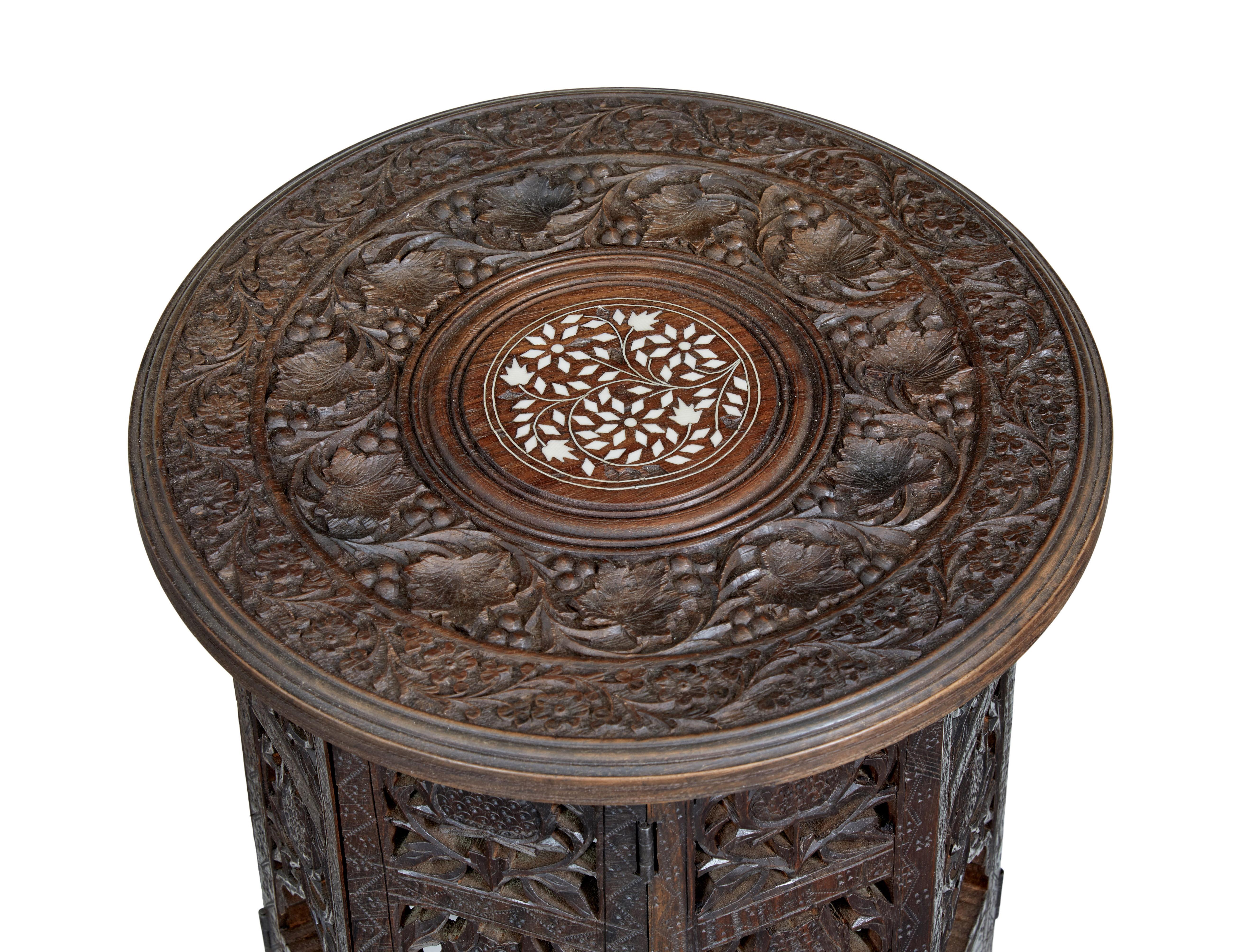 Pair of late 19th century Anglo indian carved hardwood tables circa 1880.

Good quality pair of low occasional tables.  Heavily carved and pierced hinged octagonal bases, which fold.

Circular top with inlay to the centre.

Some losses to