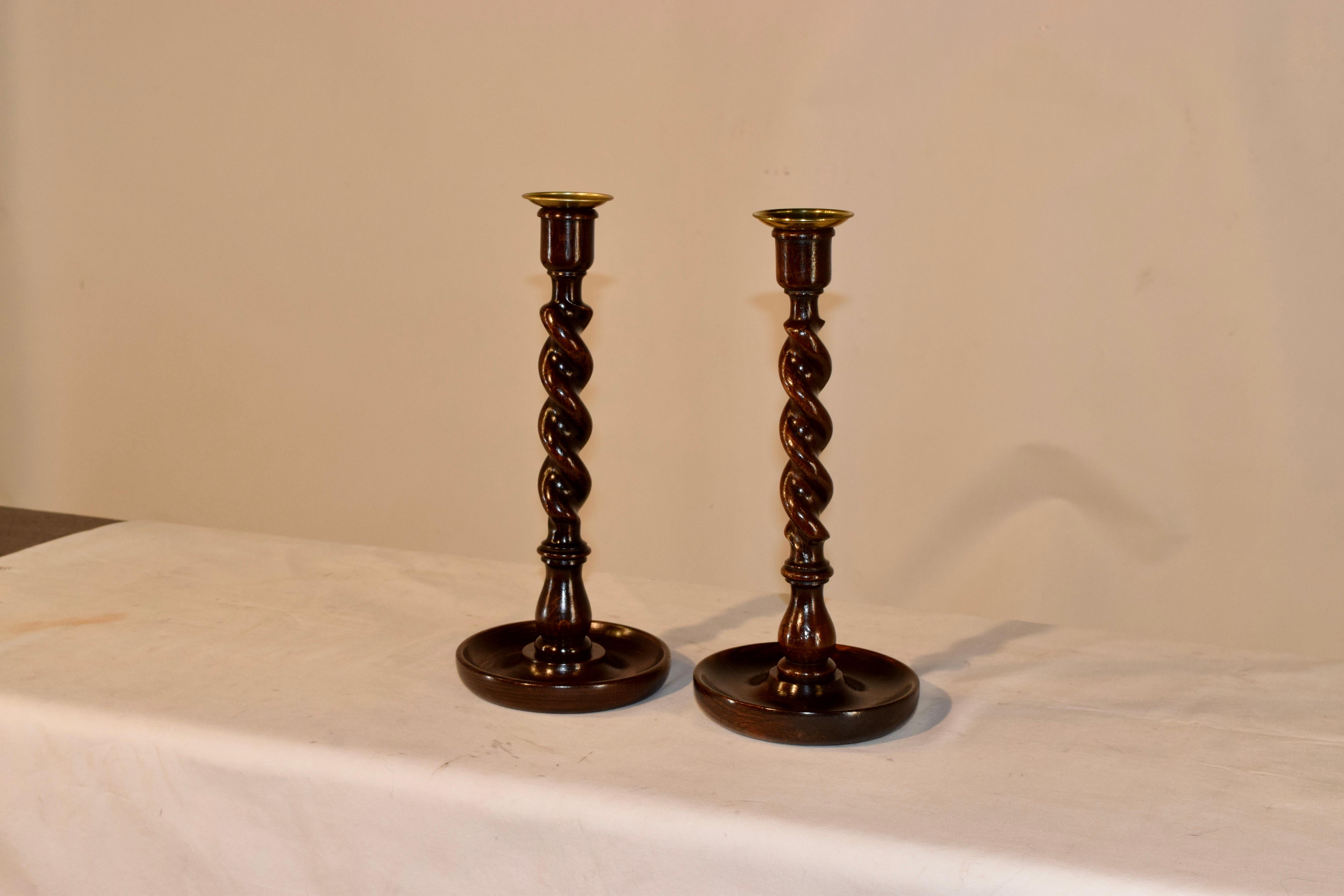 Pair of late 19th century oak candlesticks from England with a turned candle cup with original brass insert and a barley twist stem supported on a hand turned dish shaped base.