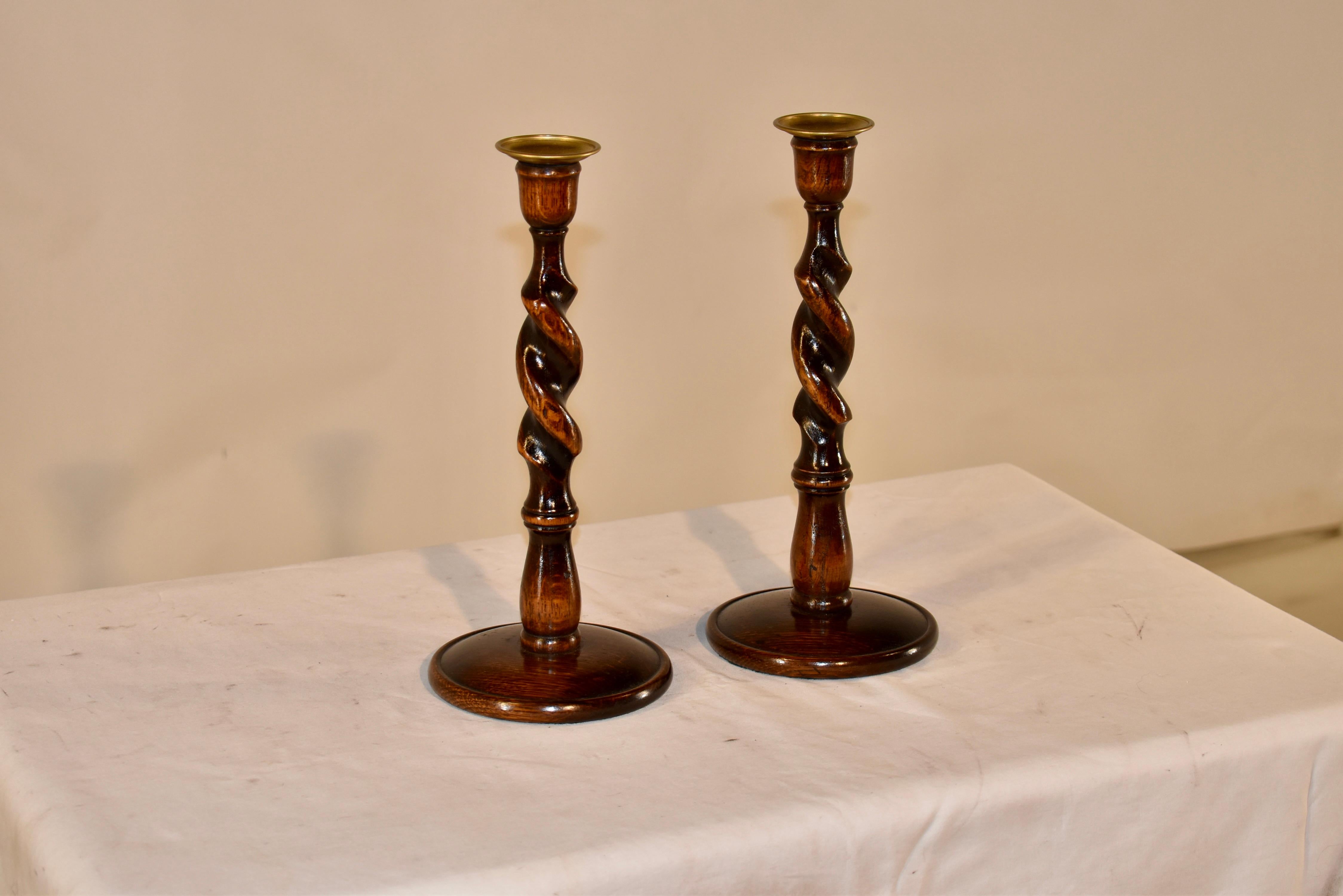 Pair of 19th century oak candlesticks from England with hand cast brass candle cups, supported on hand turned barley twist stems supported on hand turned dish shaped bases.