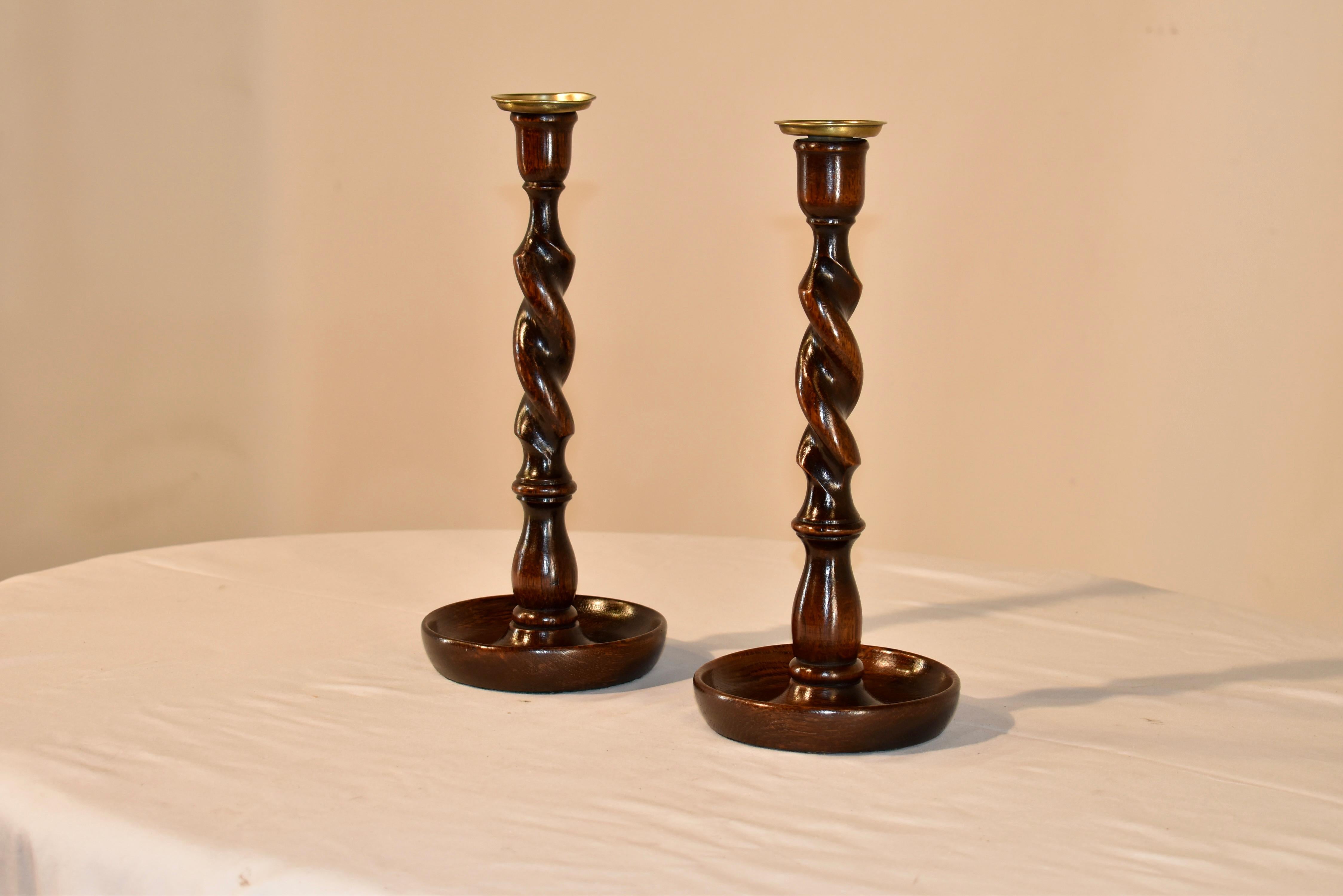 Pair of late 19th century oak candlesticks from England with a turned candle cup with brass inserts and a barley twist stem supported on a hand turned dish shaped base.