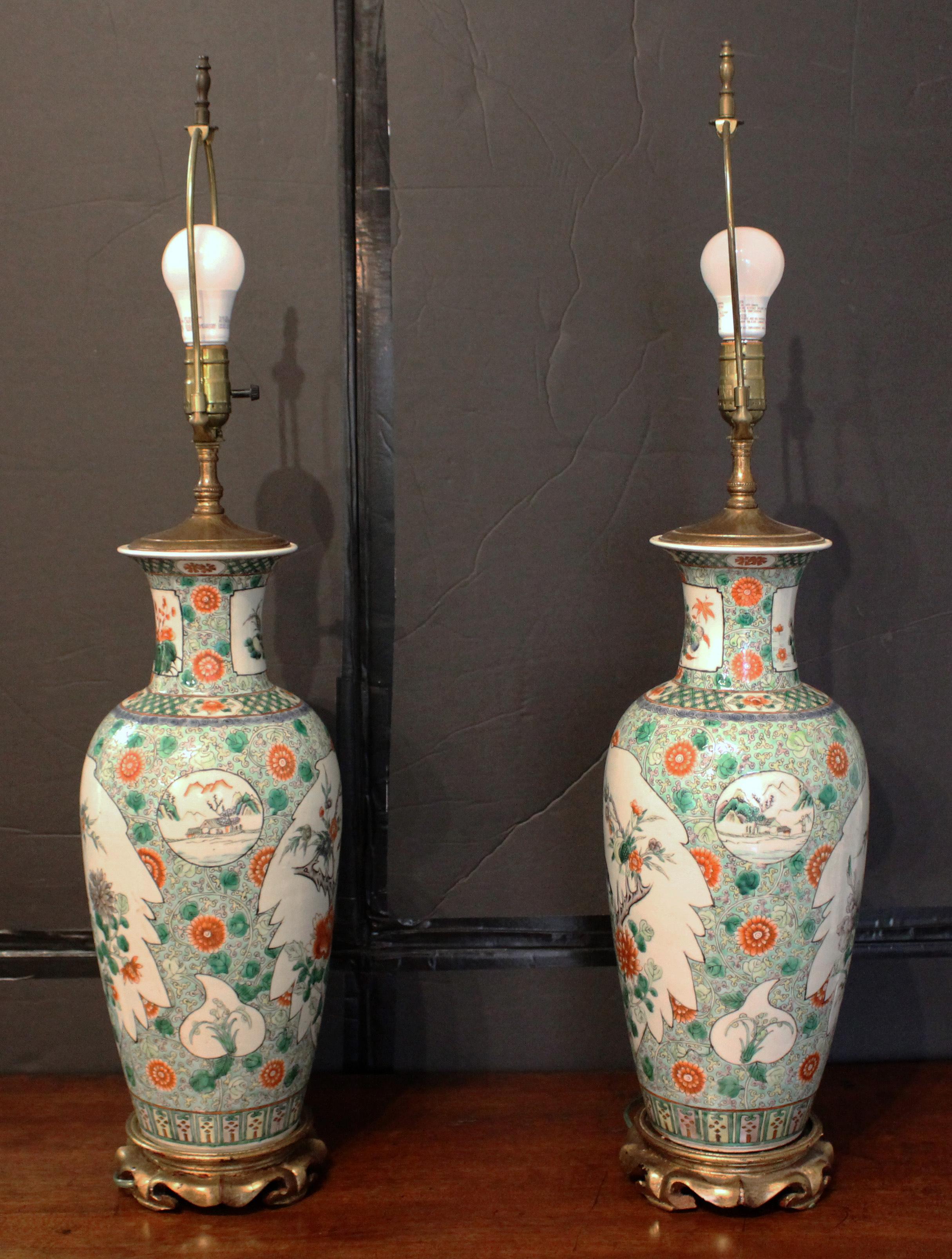 Late 19th century pair of Chinese export famille verte vases, now lamps. Carved & gilt wood bases. Decorated with small & large lozenges of birds, landscaped & fish. Both rims with minor old restorations. Qing dynasty.
25.5