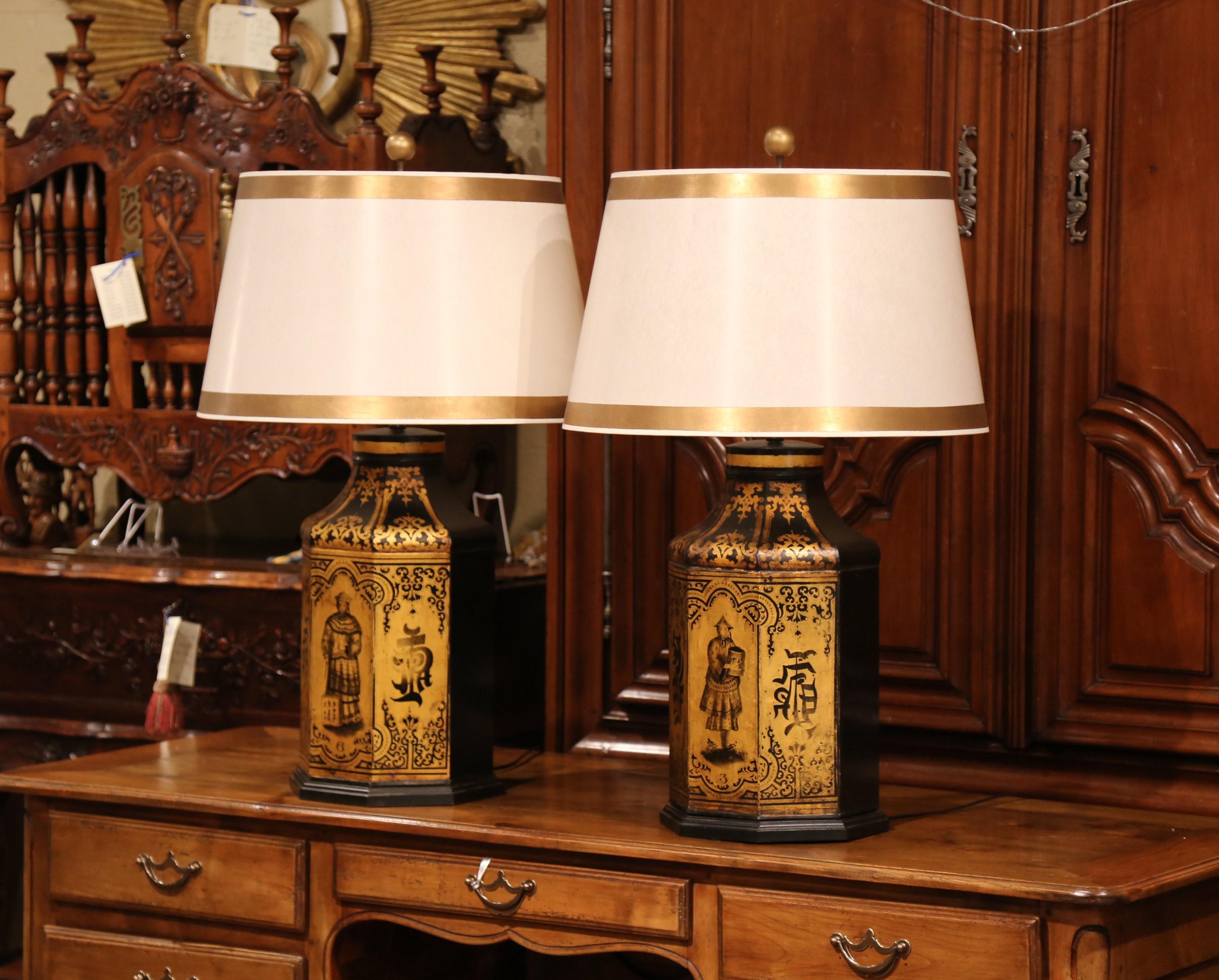 Decorate bedside tables or side tables in a living room with this elegant pair of antique table lamps. Created in England, circa 1900 and made of tole, each large tea box features exotic scenes with hand painted Chinese decor, further embellished by