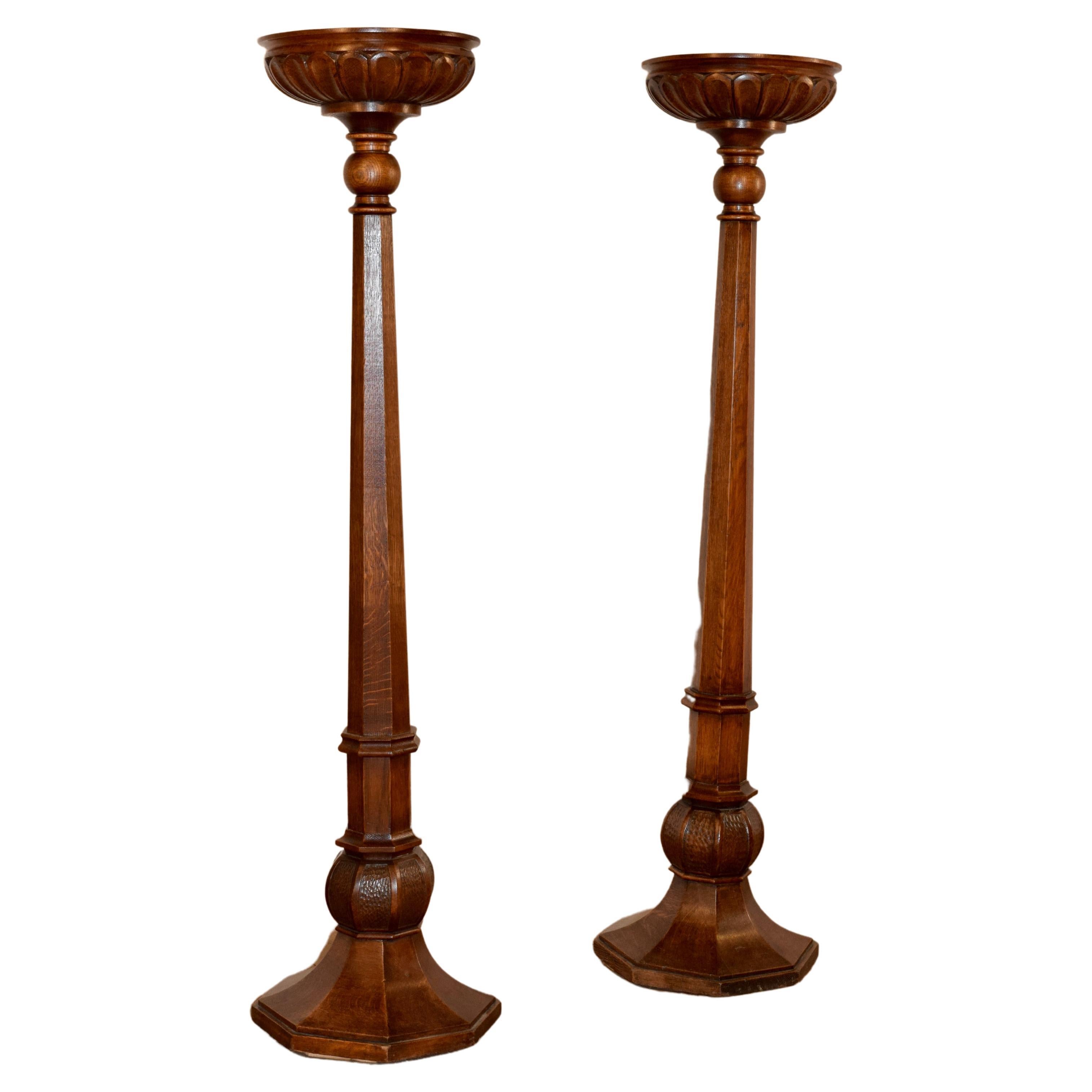 Pair of 19th century English oak pillars or torchieres with lovely carved tops over faceted columns and carved and faceted plinths.