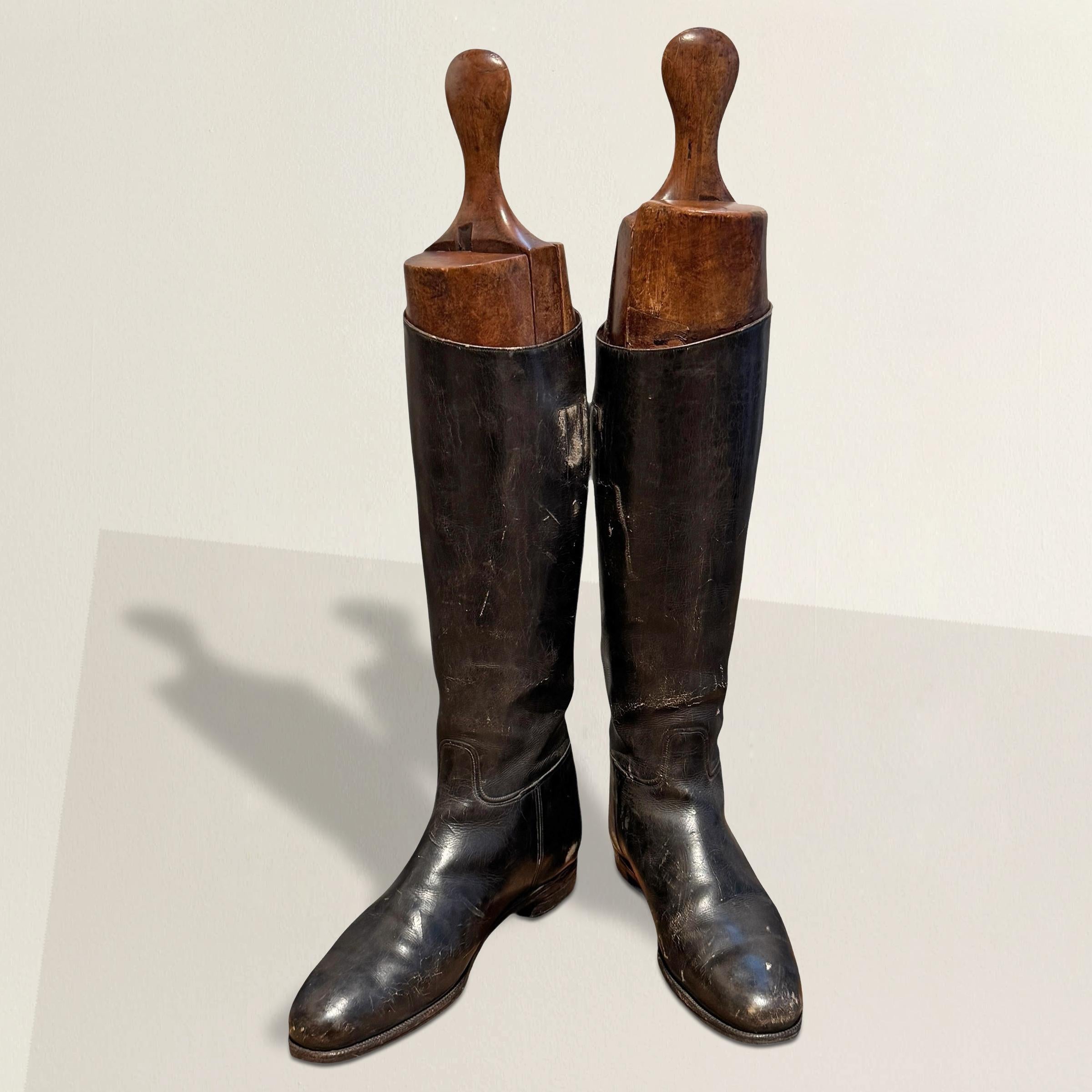 Este llamativo par de botas de montar inglesas de cuero negro de finales del siglo XIX es una hermosa reliquia de la vida deportiva. Fabricadas con un cuidado excepcional, las botas conservan sus horquillas originales de madera de cuatro piezas,