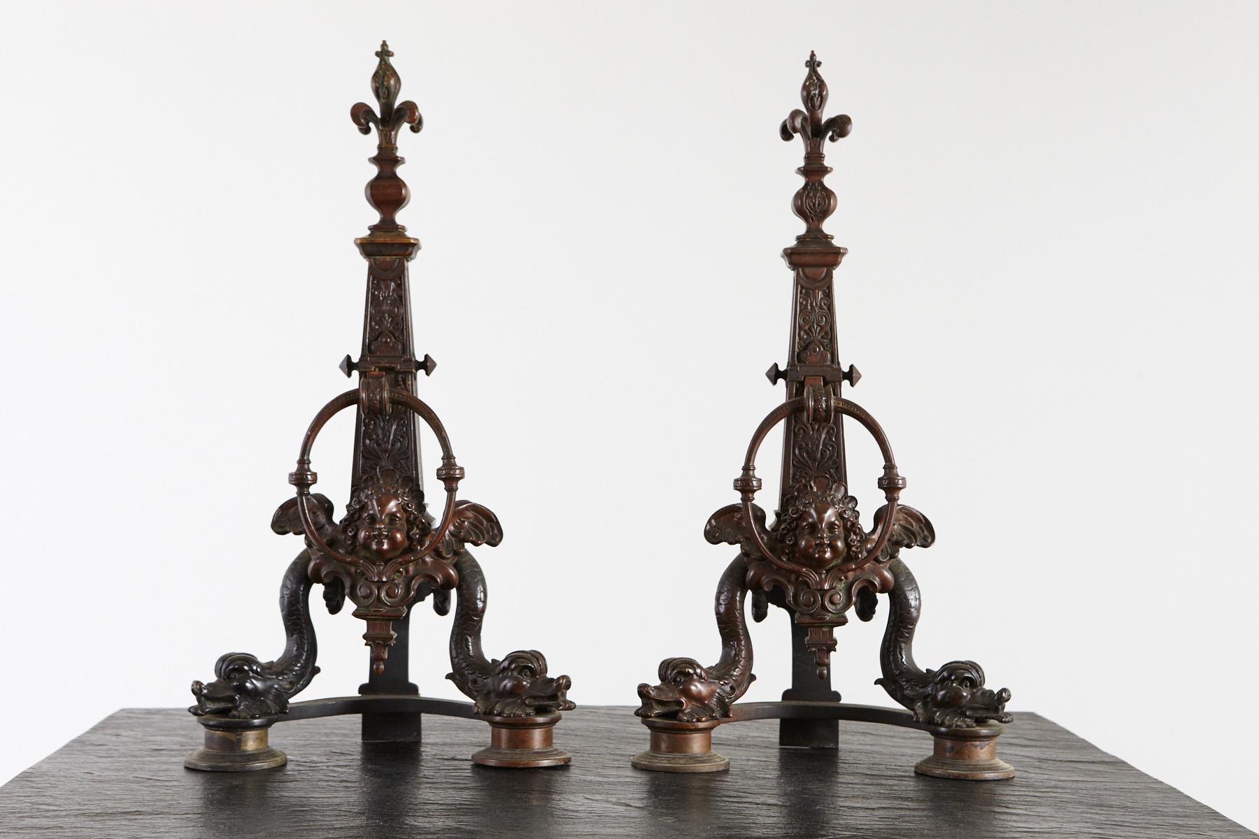 Beeindruckendes und wunderschön detailliertes Paar französischer Bronze-Chenets oder Feuerböcke aus dem späten 19. Jahrhundert, die Delphine und Putten darstellen. Ein Paar Fleur-de-Lys überragt die Obelisken.
Das Feuerböckepaar ist in sehr gutem