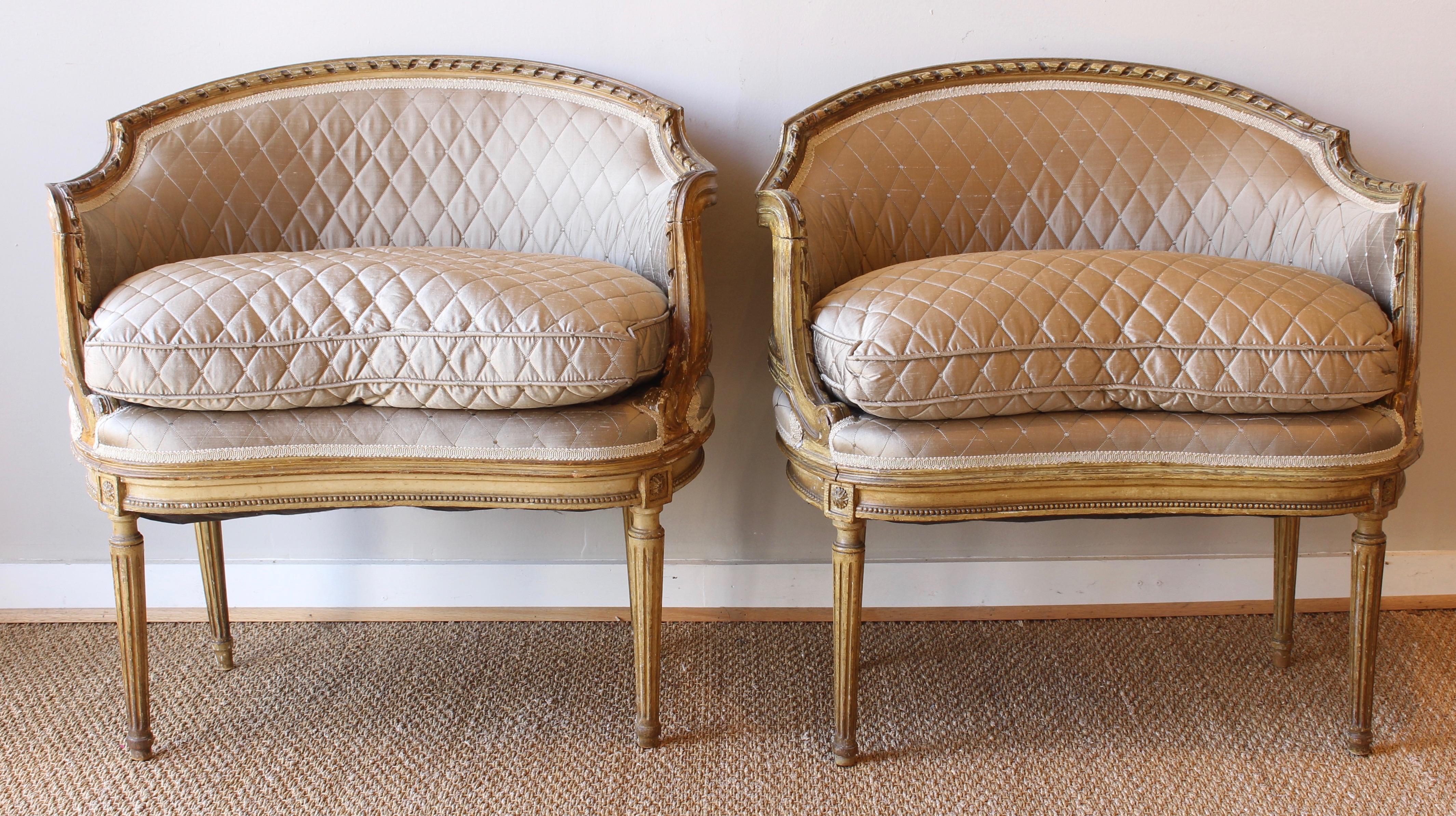 An elegant and unusual pair of late 19th C. carved and painted kidney shaped French bergeres upholstered in quilted silk fabric.