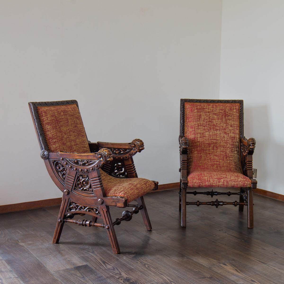 A pair of late 19th century French intricately carved walnut armchairs with stylised rams heads to the arms mixed with foliage and compass stylised legs.

  