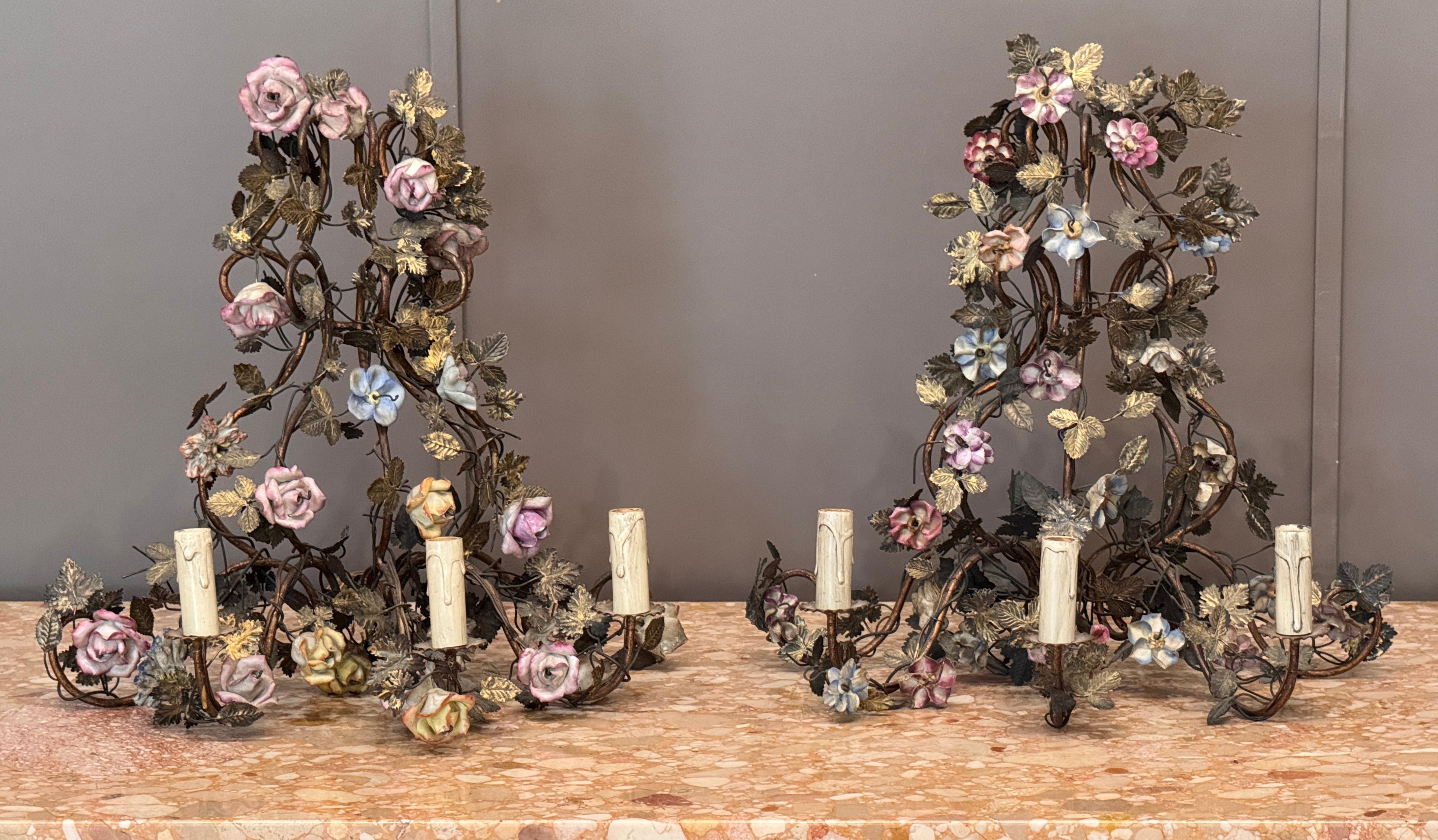 Coppia decorativa di appliques francesi della fine del XIX secolo, realizzate in ferro dorato e ornate da fiori di porcellana finemente modellati. Le viti naturalistiche, i bracci a spirale e i delicati dettagli floreali riflettono l'influenza