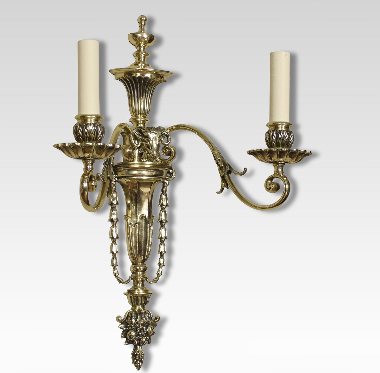 Pair of late 19th century French gilt metal wall lights the leaf scrolling arms having circular drip pans and sconces. Issuing from tapering back plate. The ornate finial above rams headed centre. The wall lights have been converted for