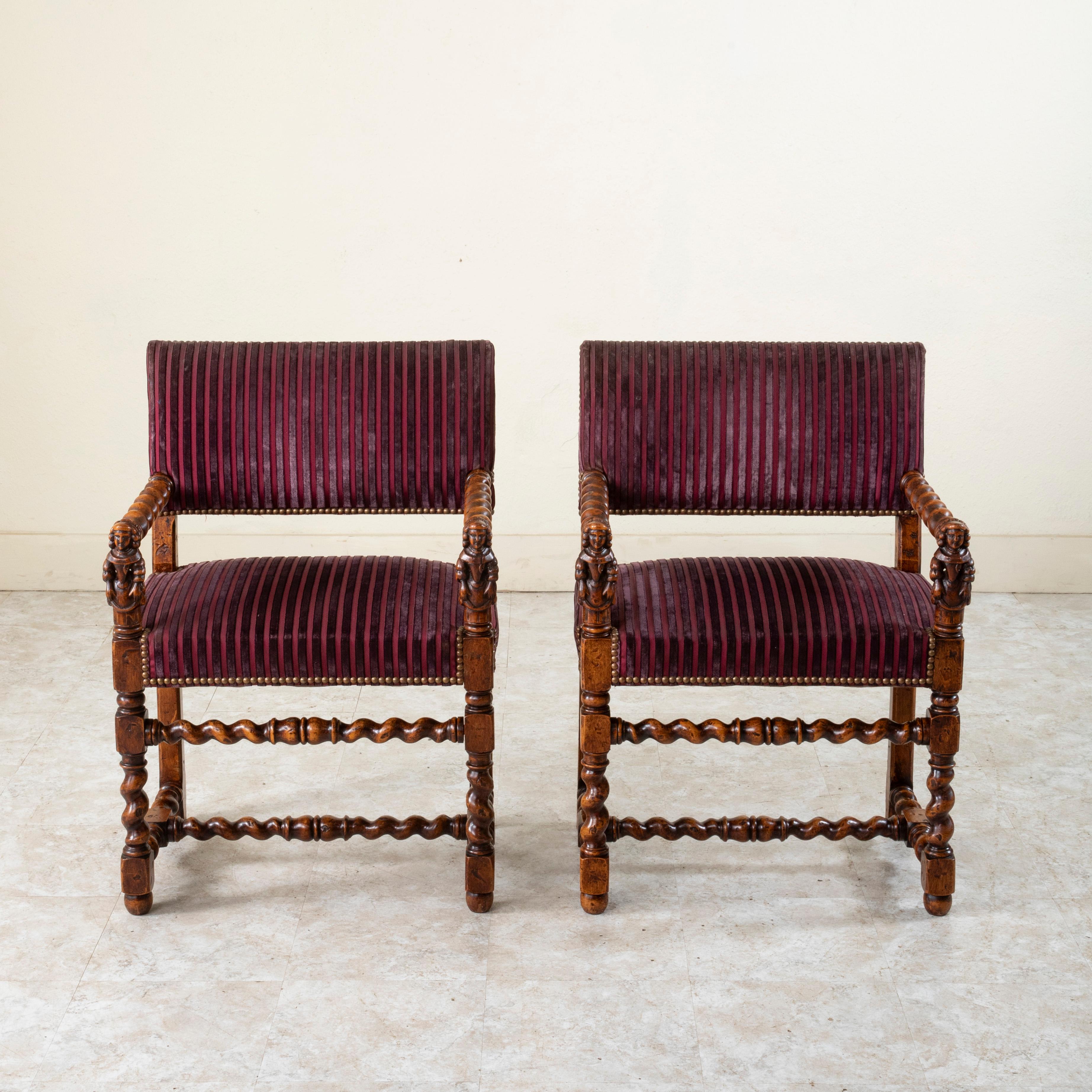 This pair of late nineteenth century French Louis XIII style armchairs features hand carved Renaissance female figures that support the hand turned barley twist armrests. The seats rest on classic barley twist legs at the front that join the squared