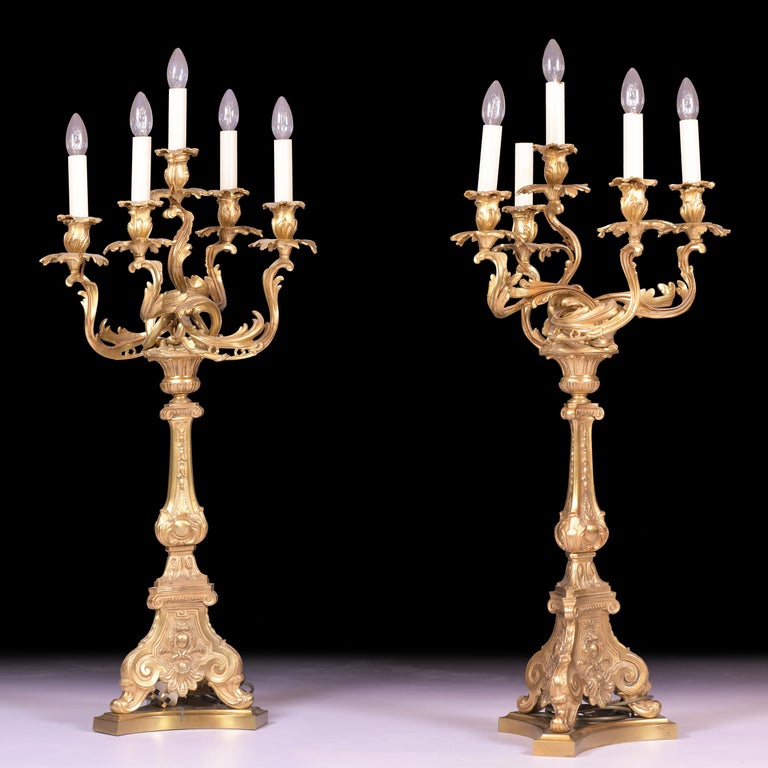 A magnificent pair of late 19th century ormolu candelabra lamps in the Louis XV style, the asymmetric acanthus scrolling arms with leafy nozzles and collars issuing from central fluted urn nozzles on foliate boss cast tripartite baluster stem