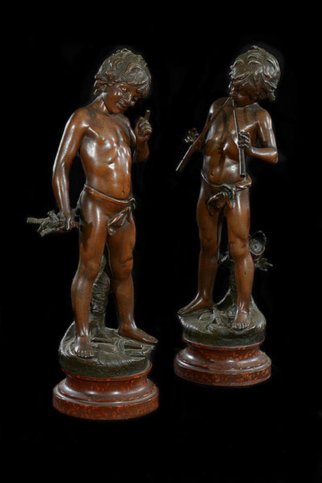 A pair of French late 19th century signed spelter figures of young boys.
One with a flute in each hand, the other holding two birds perched on twigs.
Each on a circular painted wooden stand that resembles variegated marble.
Signed and stamped in