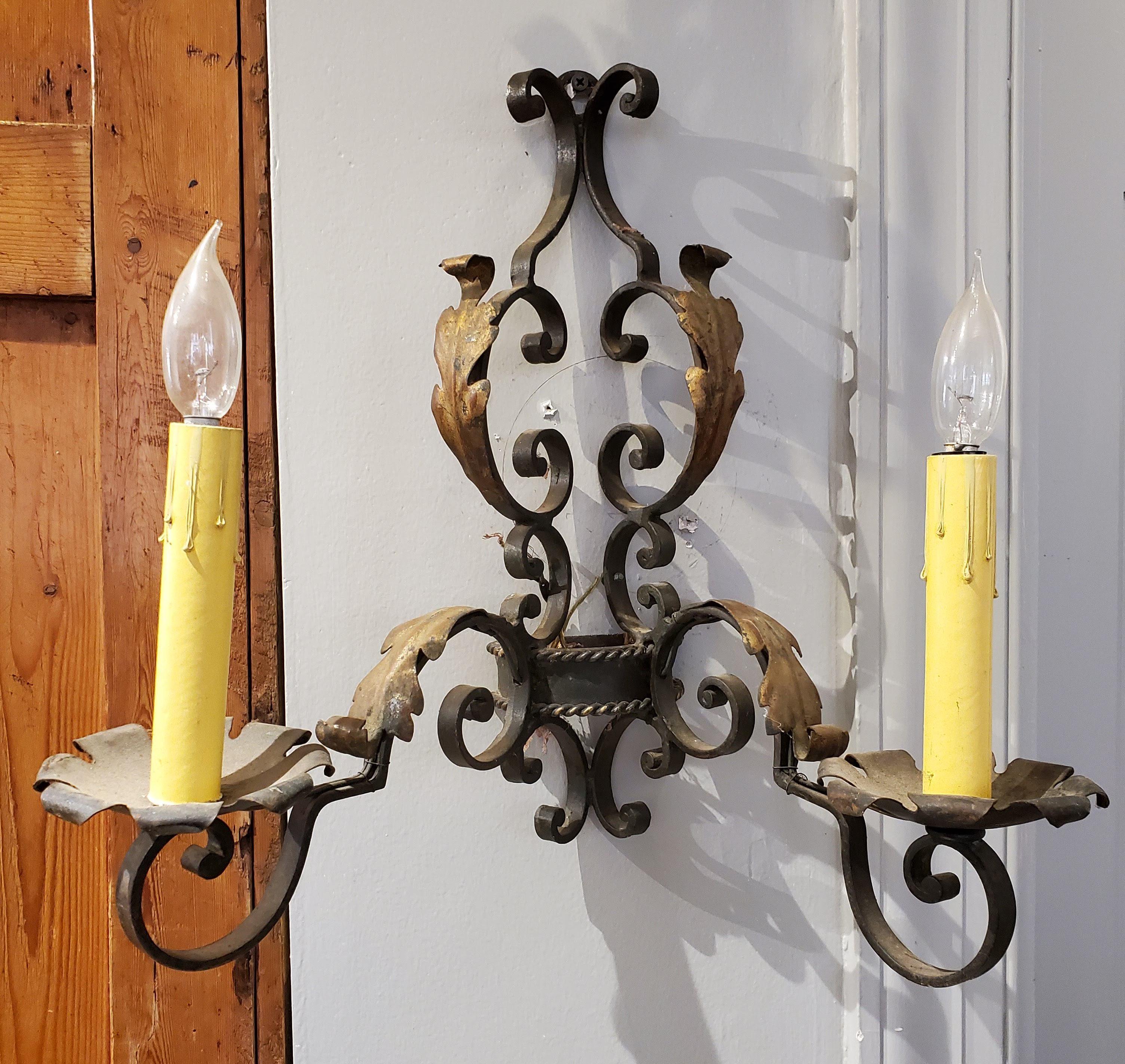 A lovely pair of Classic late 19th century french Provincial wrought iron wall sconces with two candle lights each with gilded and patinated bronze color finish. Not currently wired for electricity. Can be rewired upon request and additional