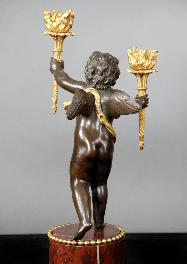A pair of late 19th century gilt and patinated bronze two-light candelabra.

Both cherubs holding a torch in each hand, standing on a marble base.