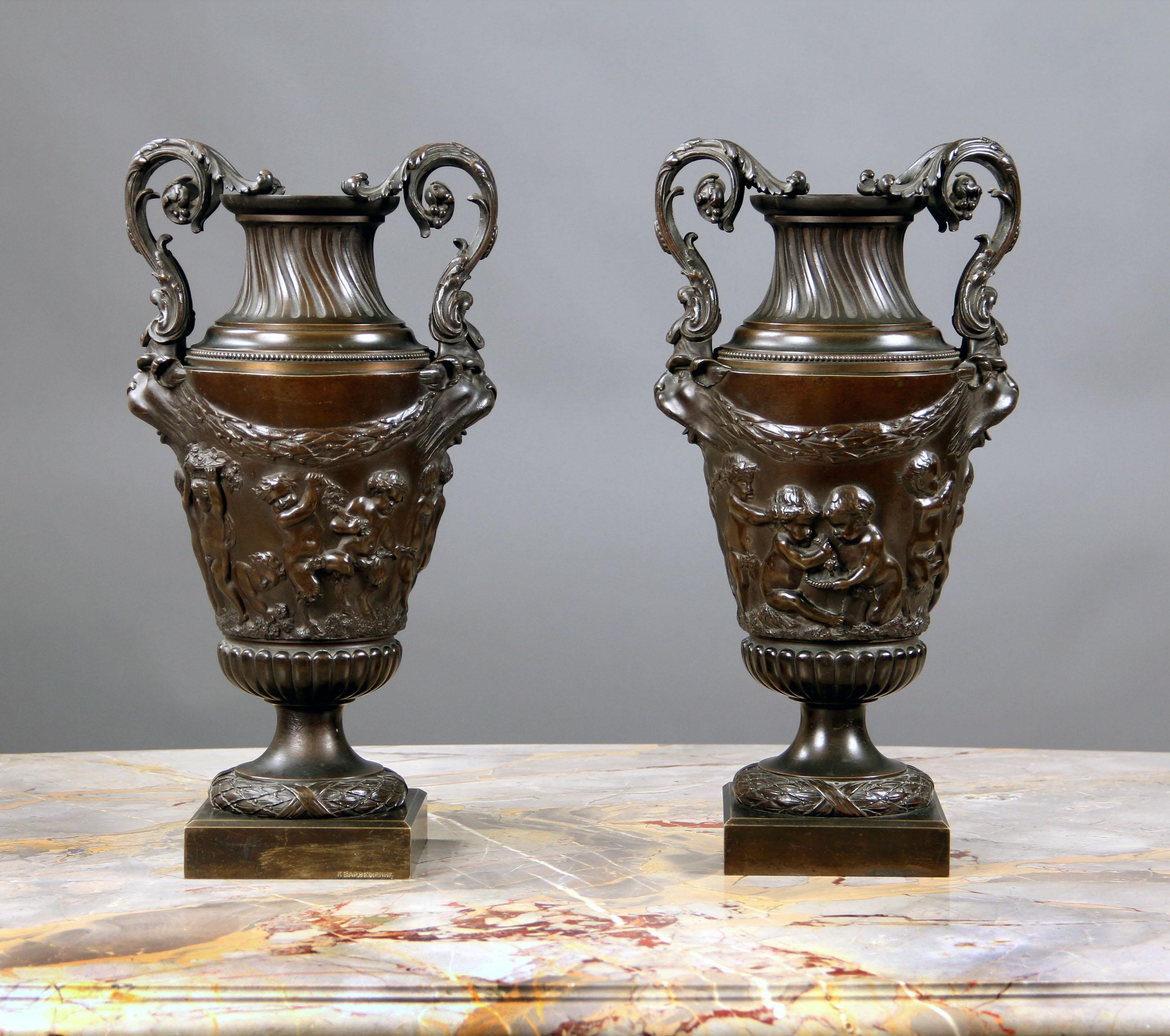 A pair of late 19th century patinated bronze vases after Claude-Michel Clodion.

After Claude-Michel Clodion

Each vase of tapering form applied with two grotesque masks hung with laurel garlands above a frieze cast in relief with depictions of
