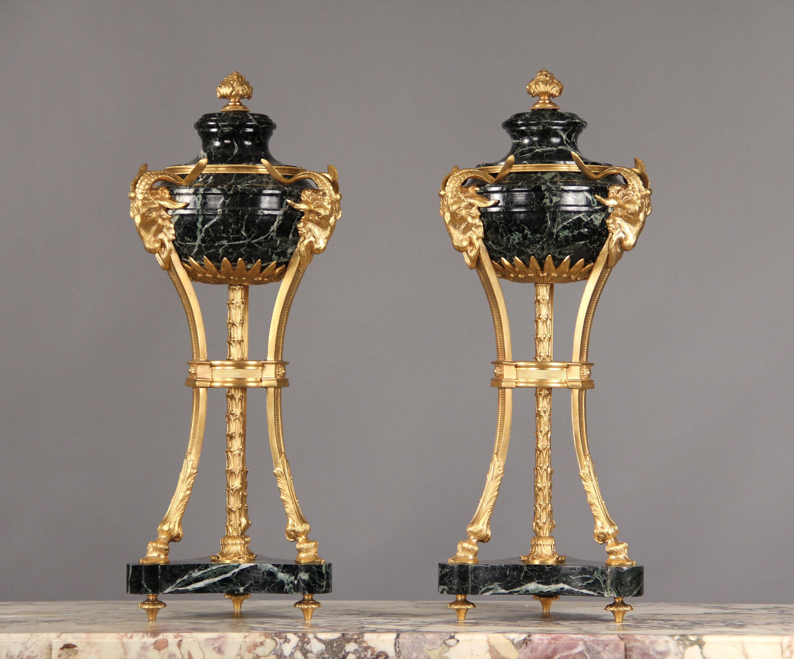 A pair of late 19th century gilt bronze-mounted Verde Antico marble Cassolettes

Each with a removable lid, marble body surmounted with three bronze ram heads.