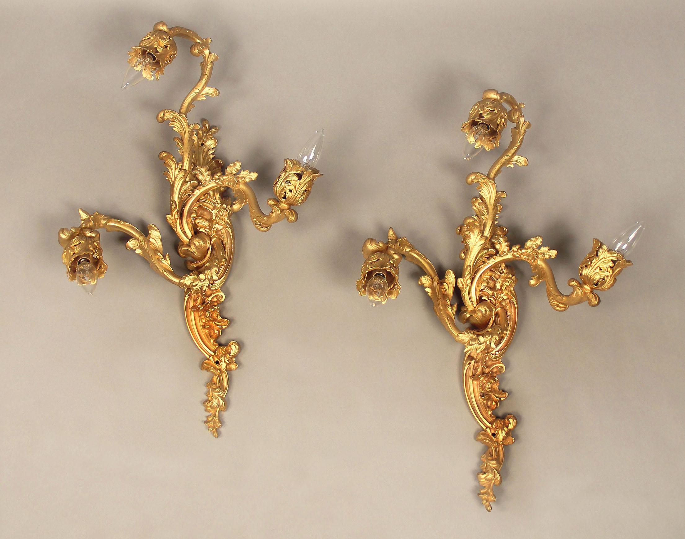 A pair of late 19th century gilt bronze three-light sconces

The backplate and arms decorated with flowers and foliage.